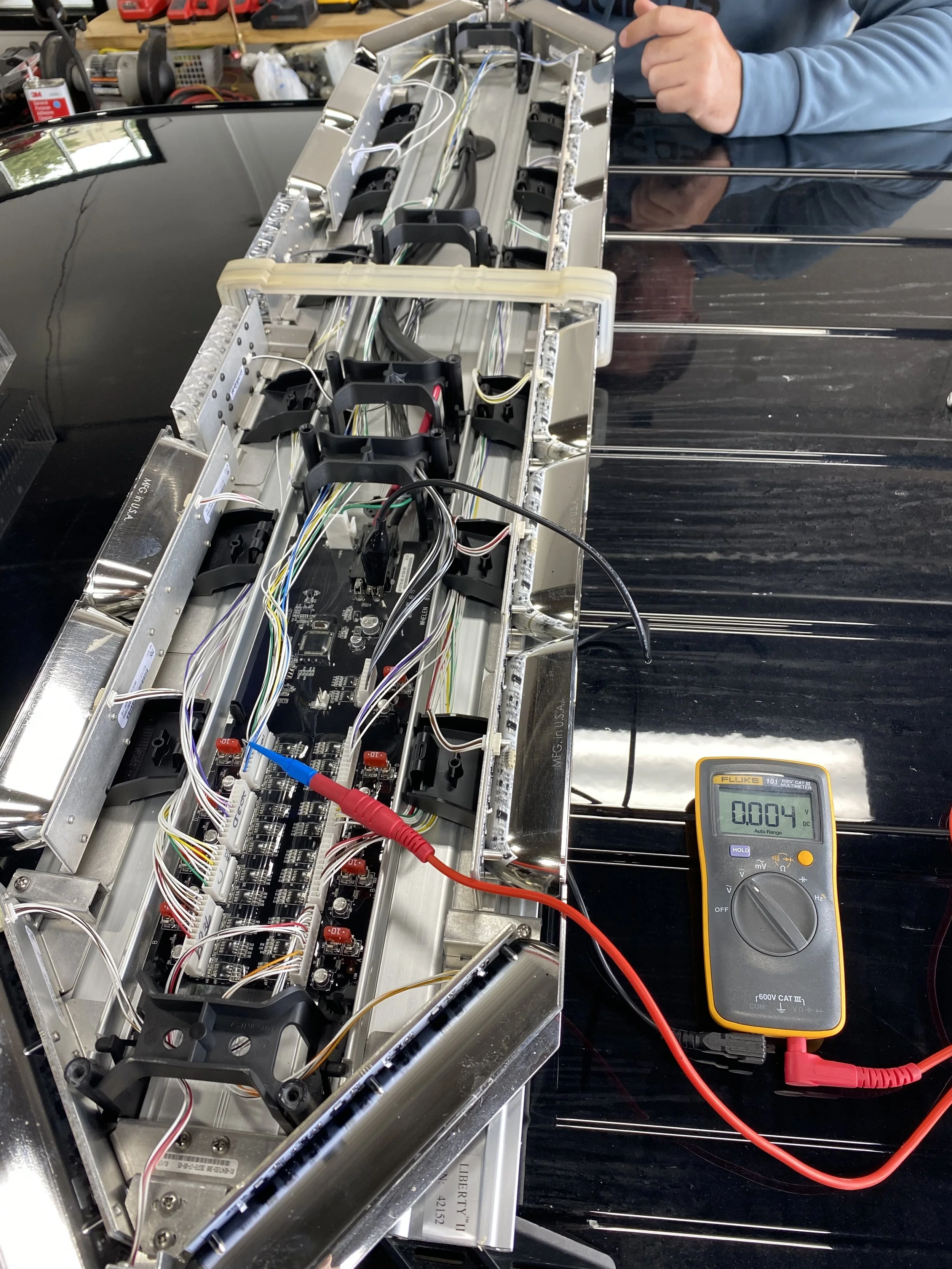 Emergency vehicle lightbar wiring and electronics being tested with a multimeter