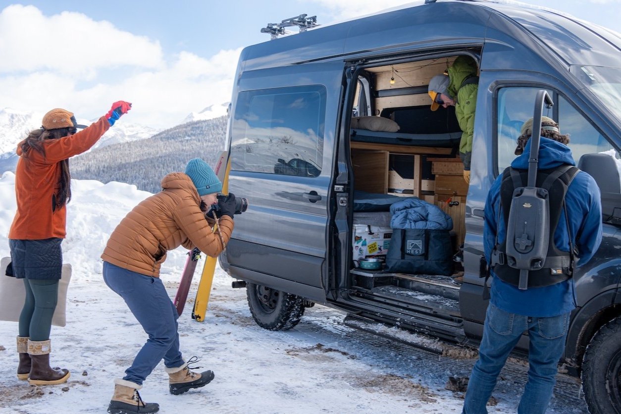Photographer capturing an outdoor brand HEST campaign beside a camper van in winter.