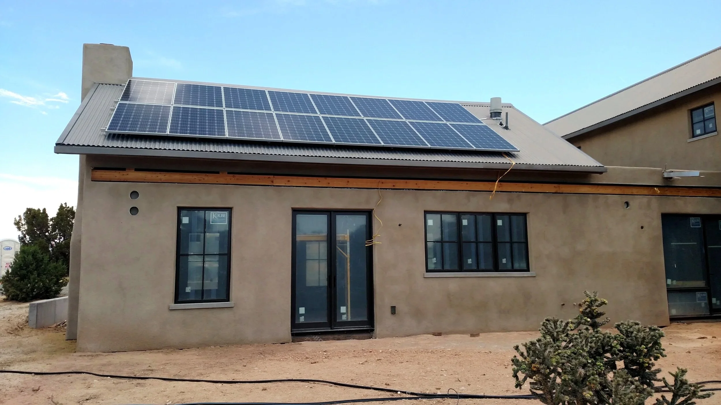 A newly built home with solar panels installed on the roof, under a blue sky.