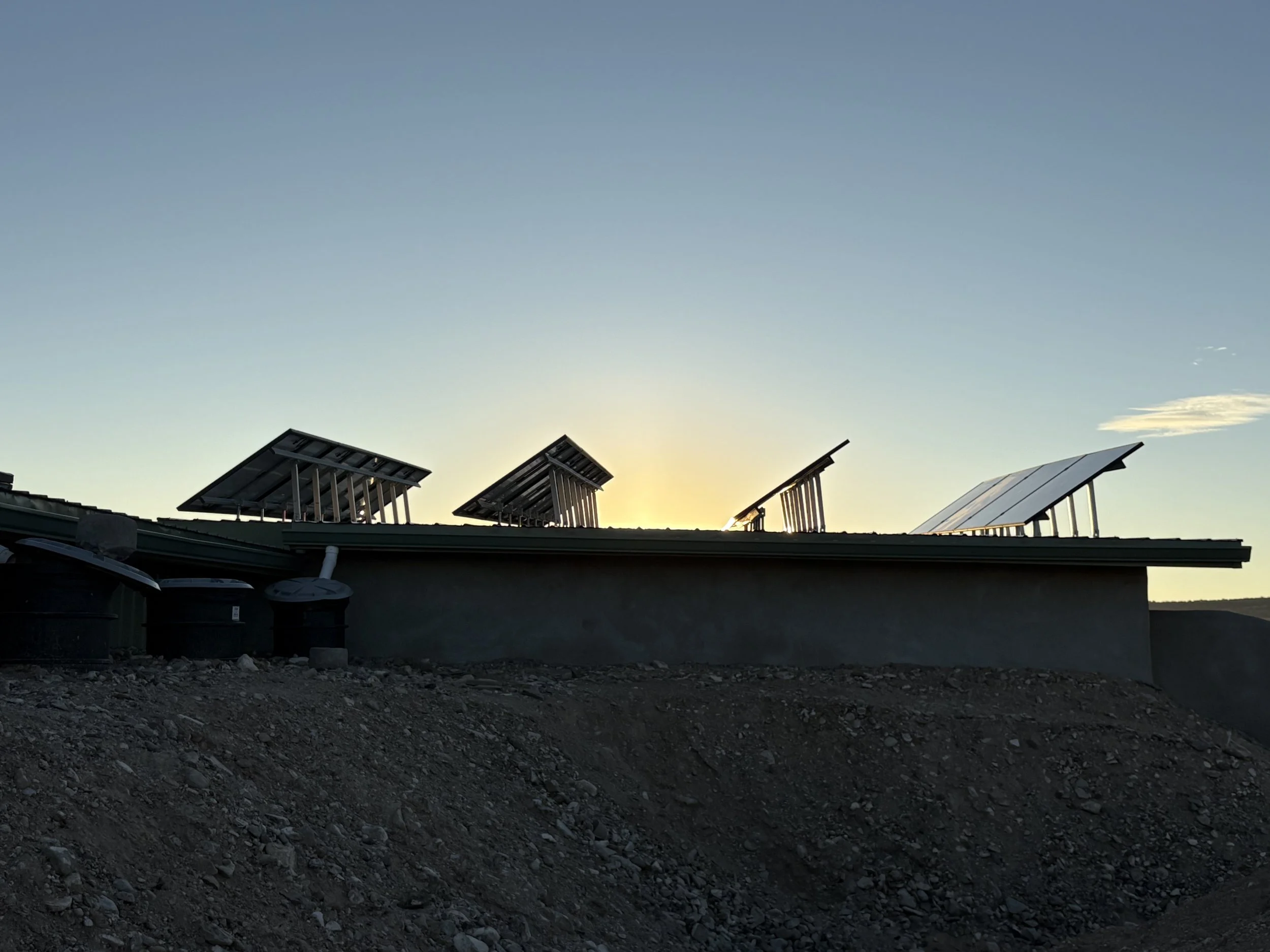 Photo of solar panels installed on a rooftop against a clear sky during sunset or sunrise.