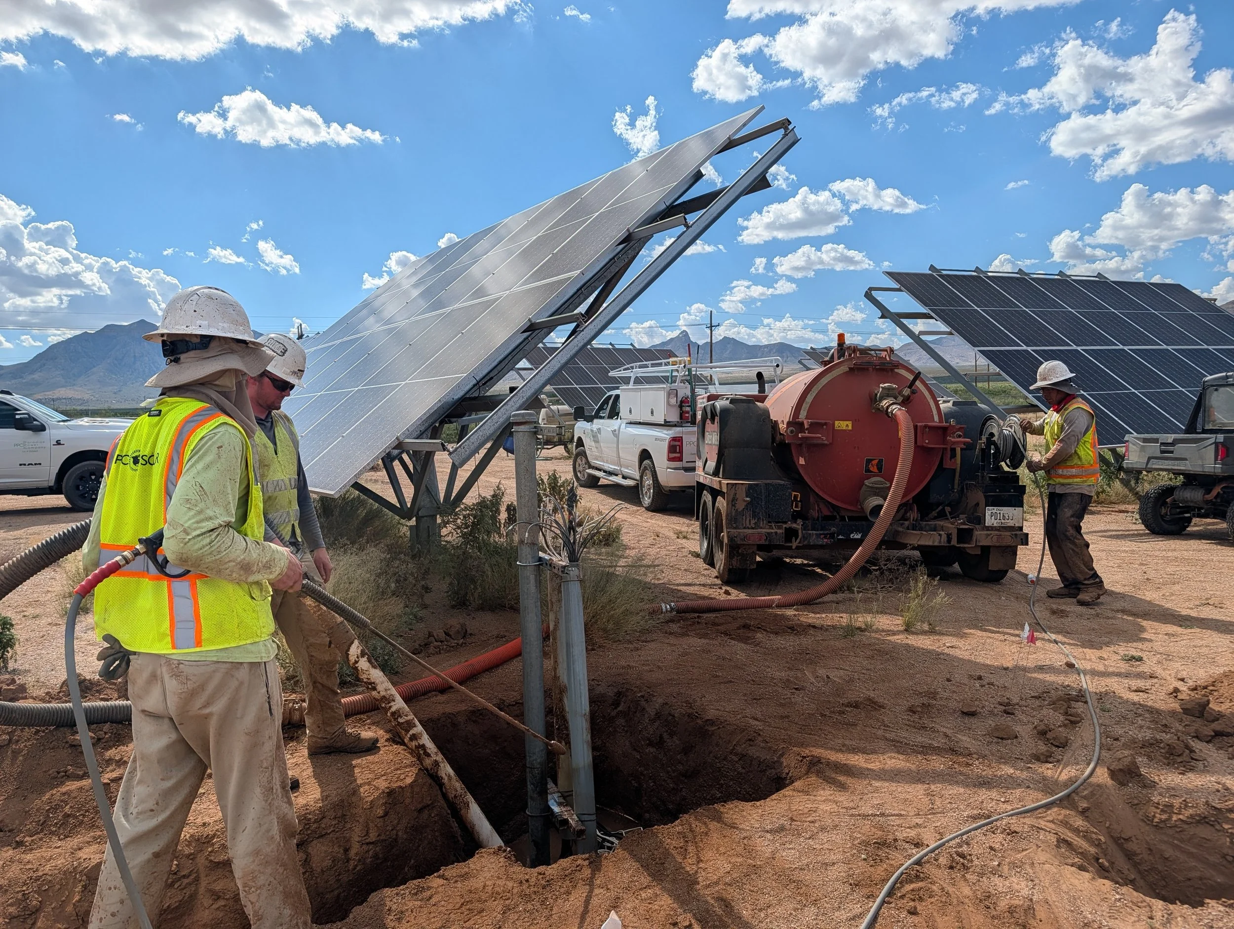 Construction workers in desert setting working on solar repower project with trenching in hot weather.