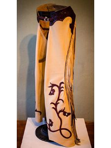 Made of top-grain cow hide, the cream fringe is hand scalloped and buck-stiched in kangaroo which is framed with two rows of stitching. The dark brown piping and fringe is top-grain deer-tan cowhide. Each flower on the leg features custom-made concho
