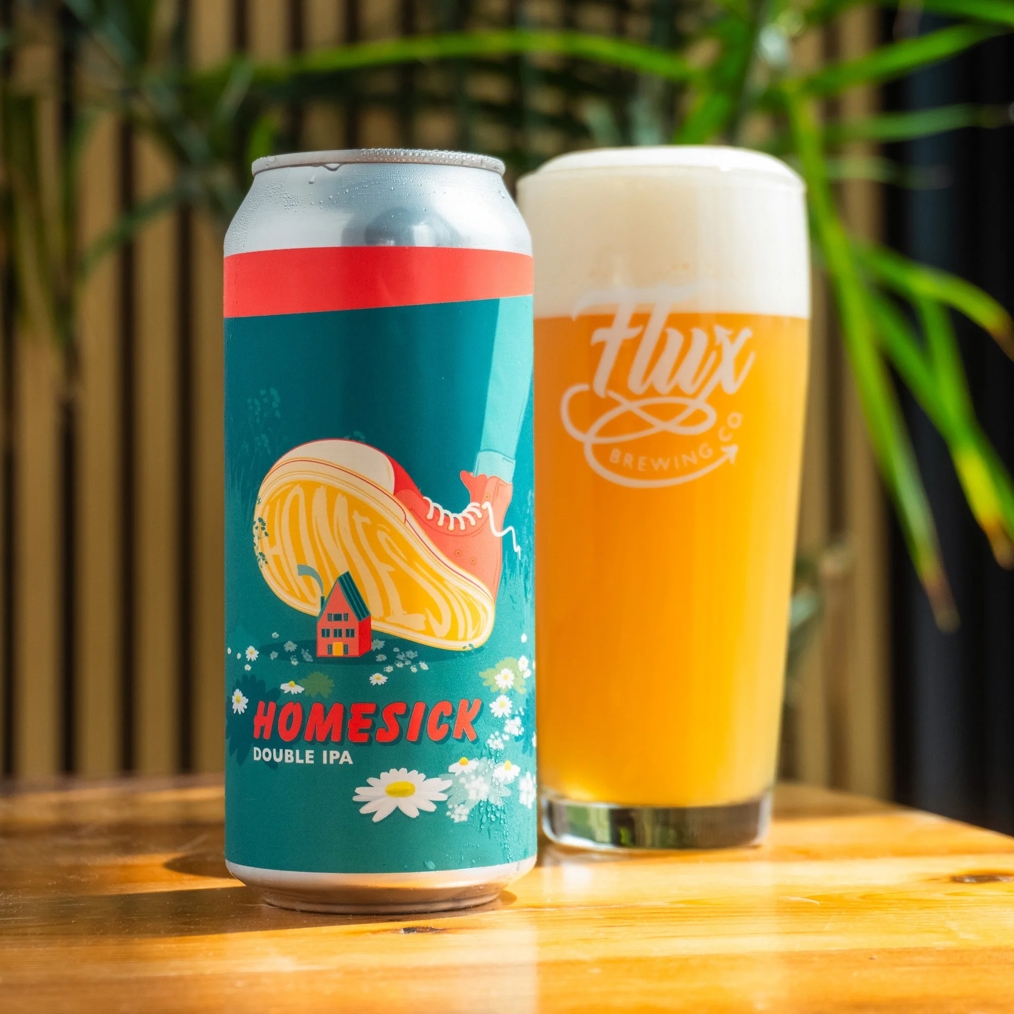 A colourful can of Homesick craft beer, featuring a design with a foot crushing a little house.