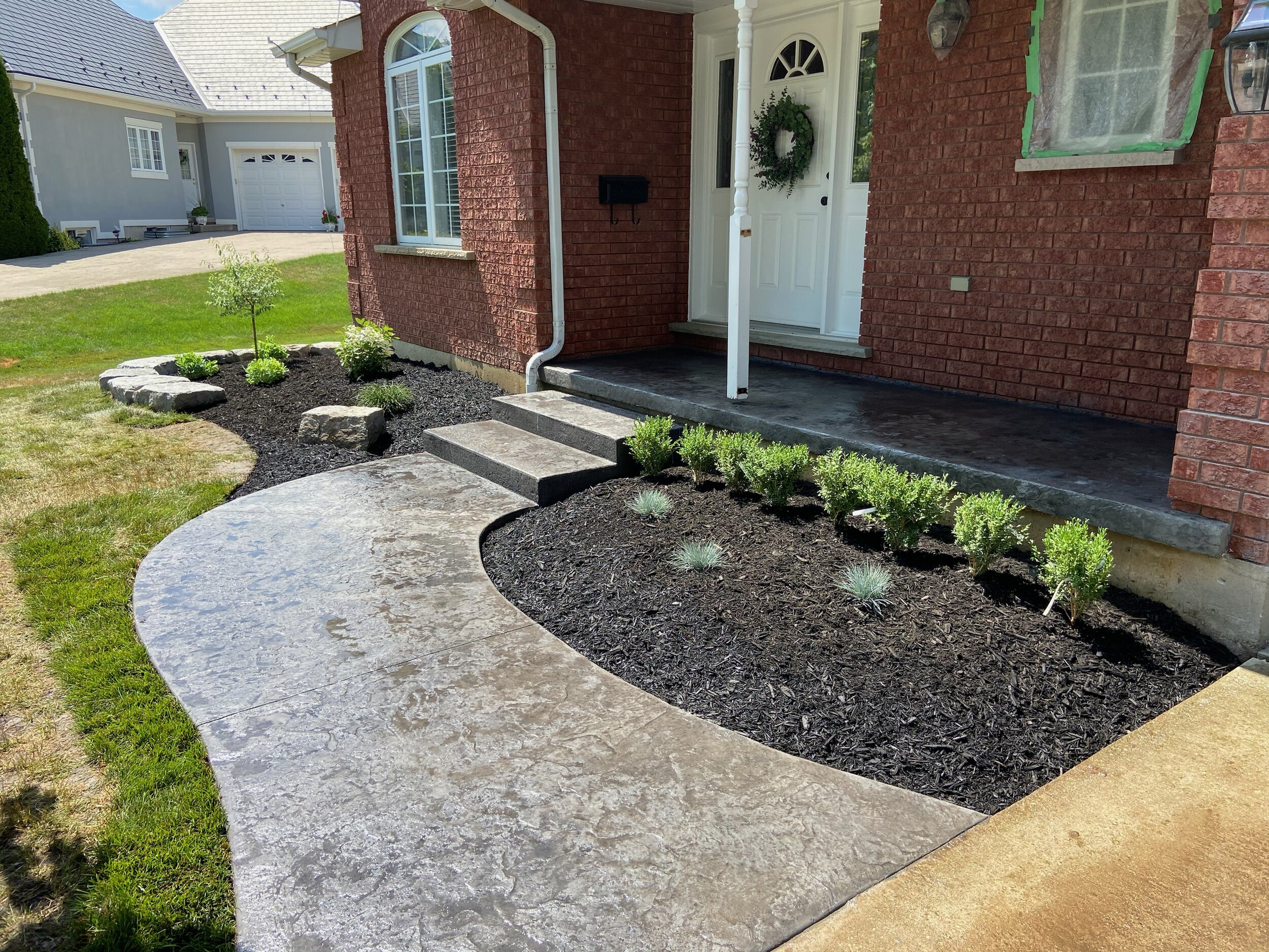 House front yard with landscaped garden and concrete walkway.