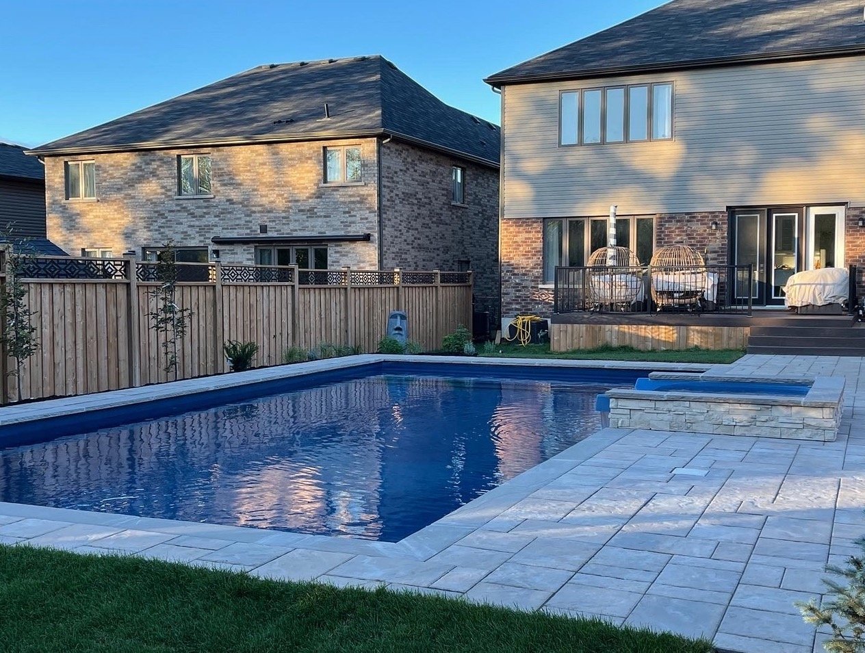 Two-story brick houses with a pool in the backyard, wooden fencing, patio with seating, and landscaped area.