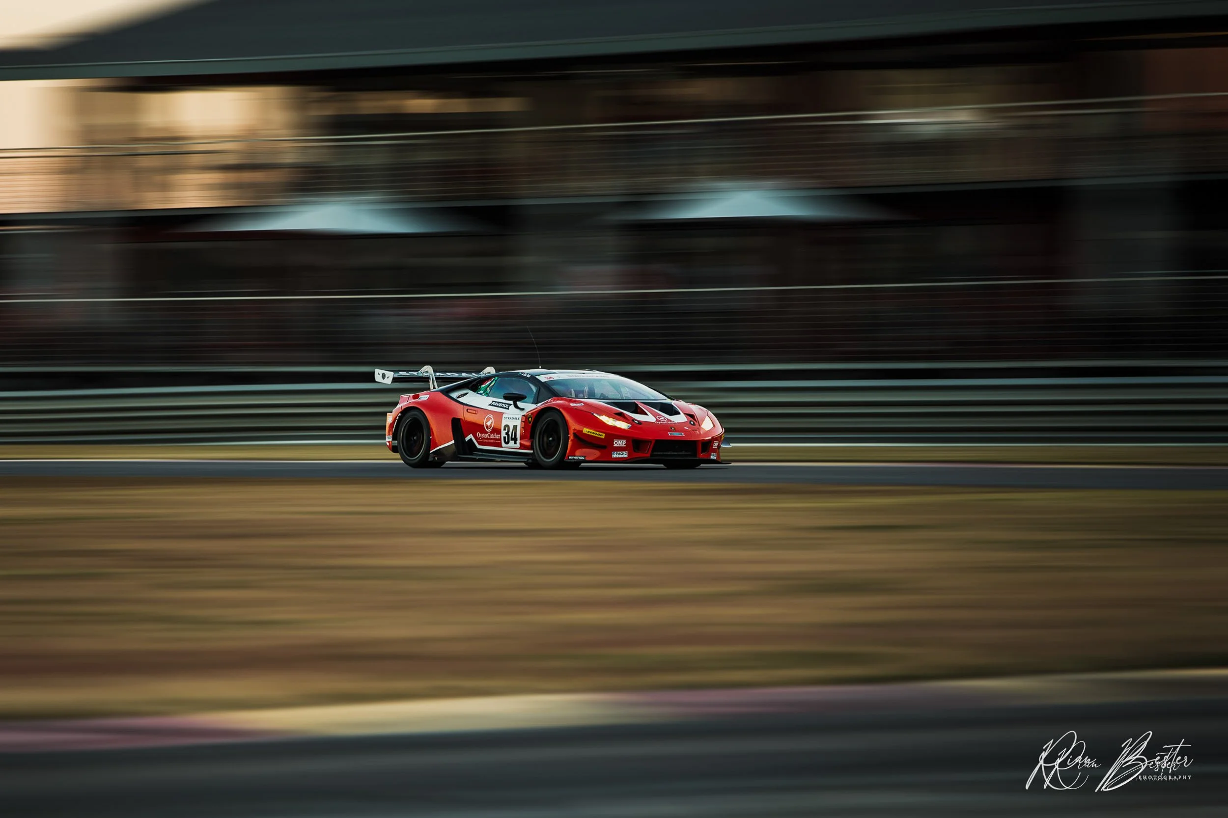 A red and black racing car speeding on a race track with a blurred background.