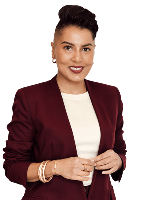 Sharon Pakir standing in a burgundy suit looking directly at the camera and smiling
