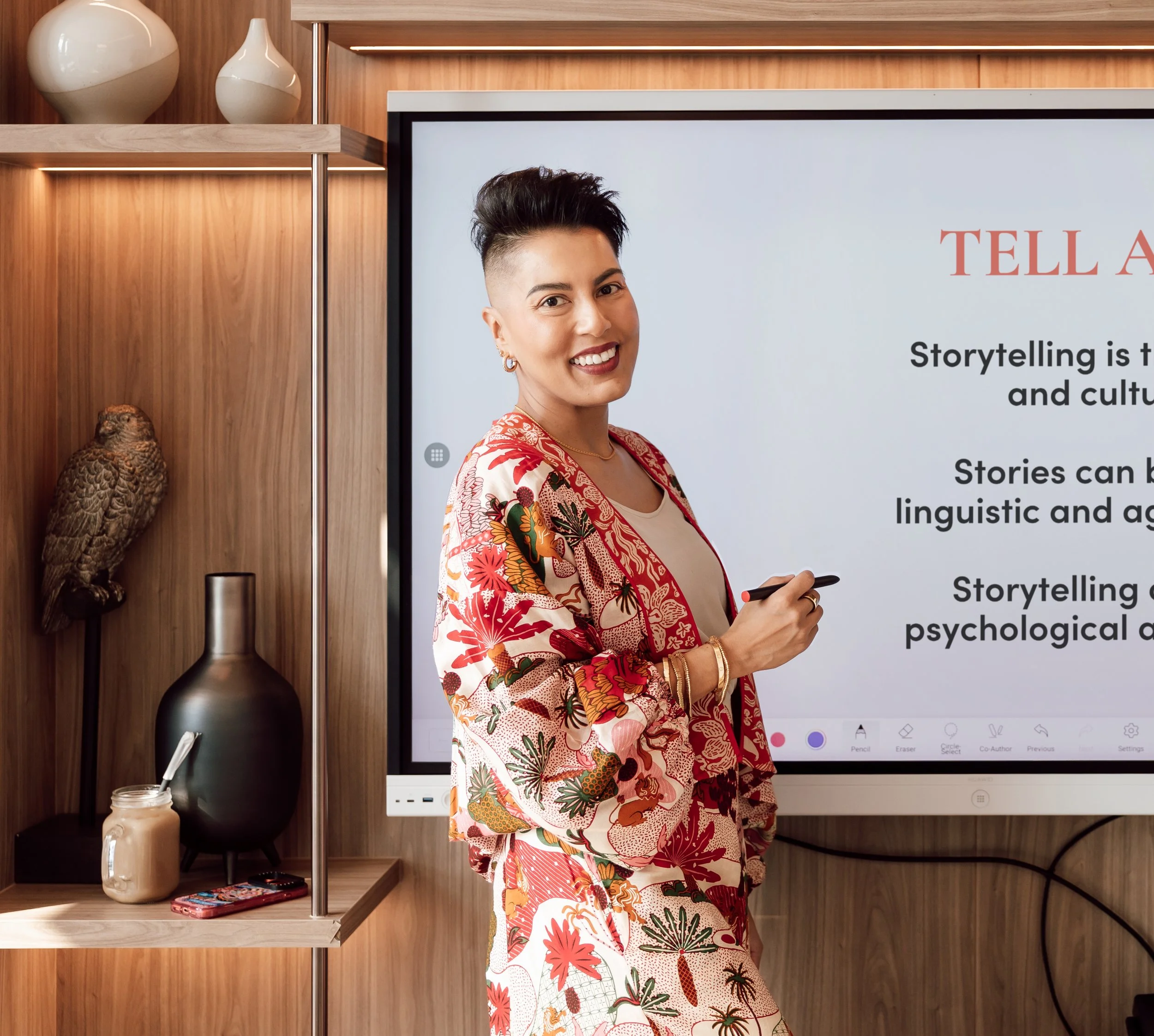 Sharon Pakir wearing a vibrant patterned suit, delivering corporate leadership training in a corporate boardroom
