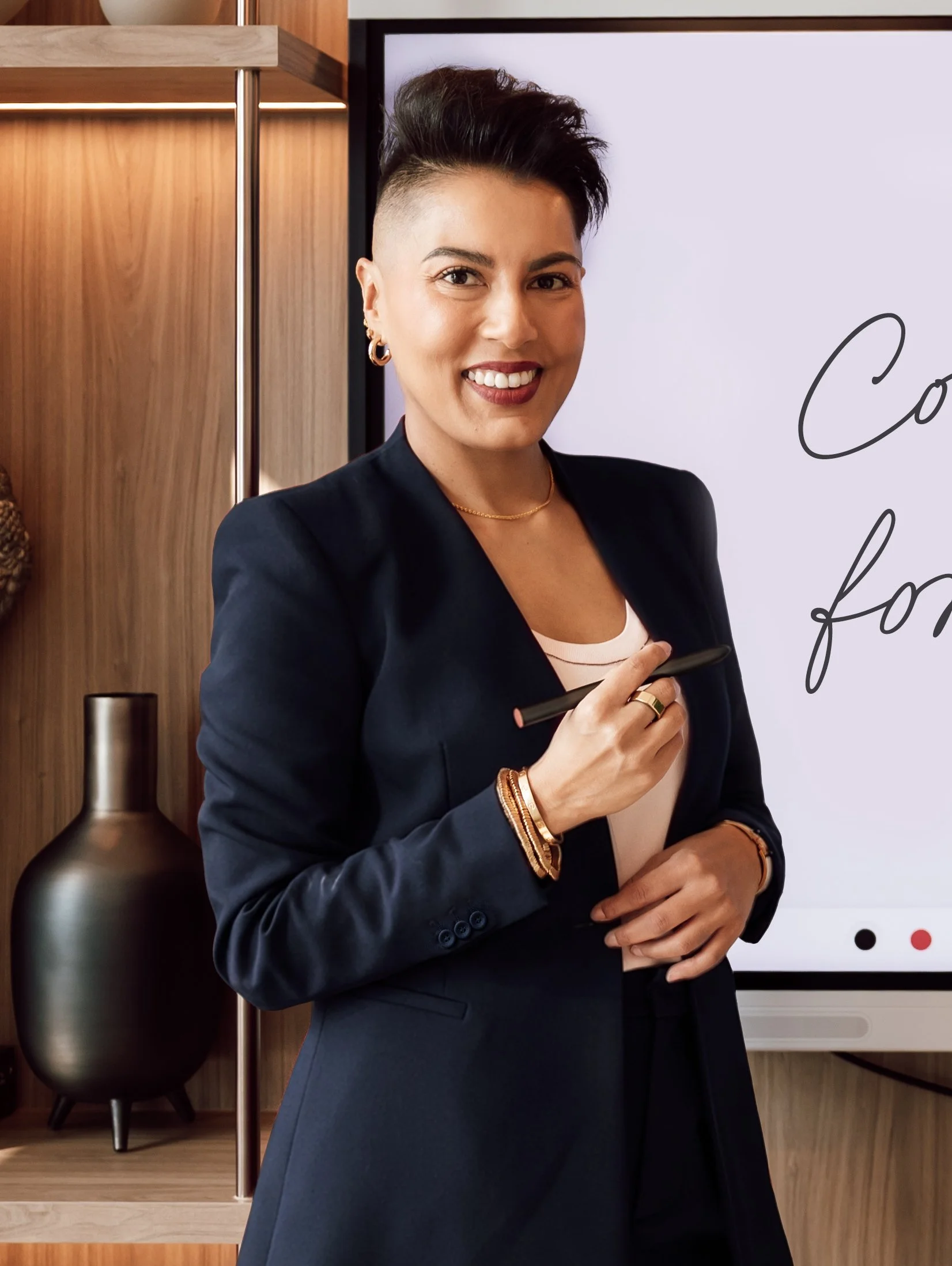 Sharon Pakir standing in front of a digital screen while delivering corporate leadership training in the GCC