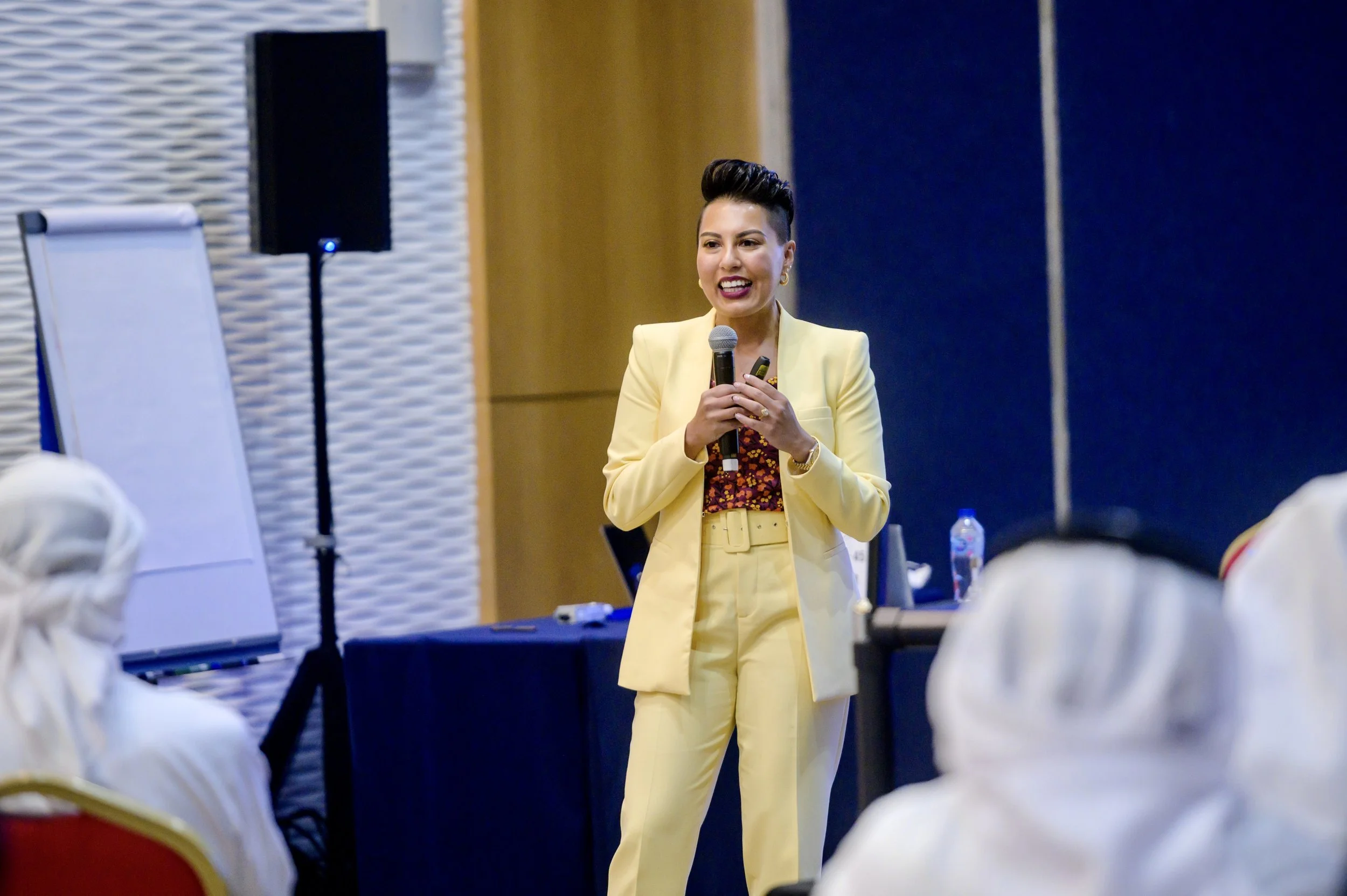 Sharon Pakir on stage speaking to a crowd of people in the UAE