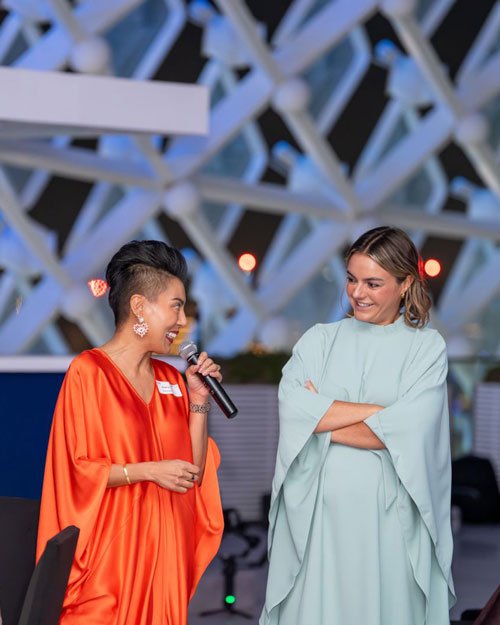 Sharon Pakir engaged with a female participant on stage at an event