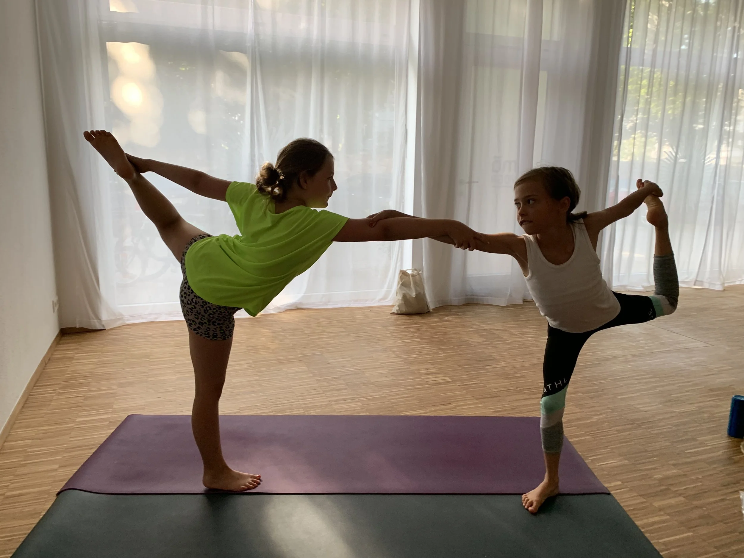 Kinder bei einer spielerischen Yogaübung mit Partner in der Schule