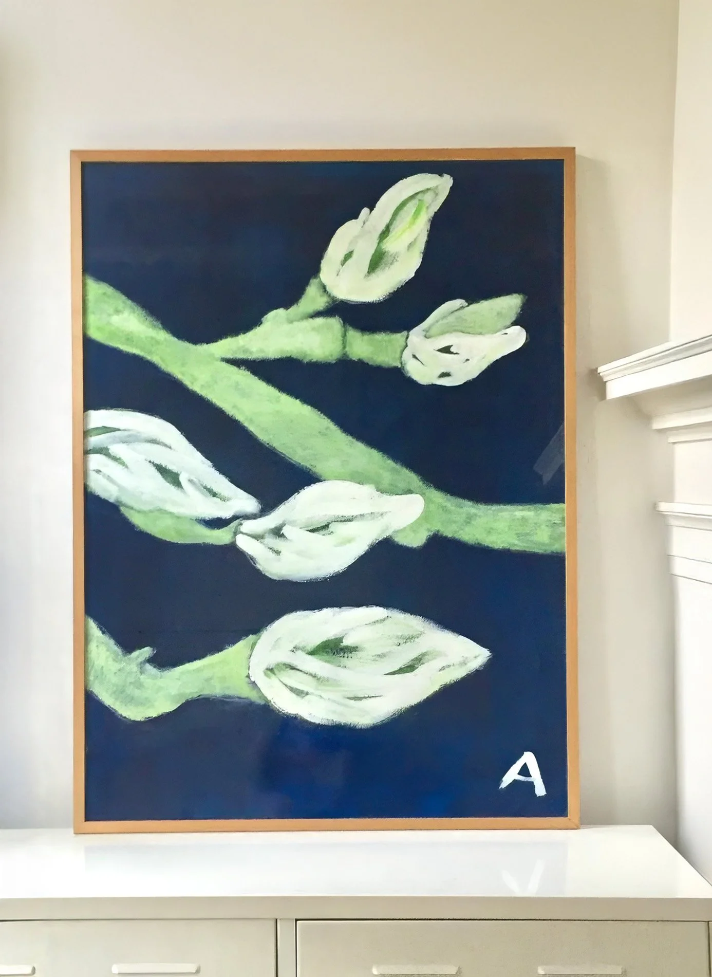 Schilderij van Anna de Leeuw met witte bloemen op een donkere blauwe achtergrond, ingelijst met een lichte houten lijst.