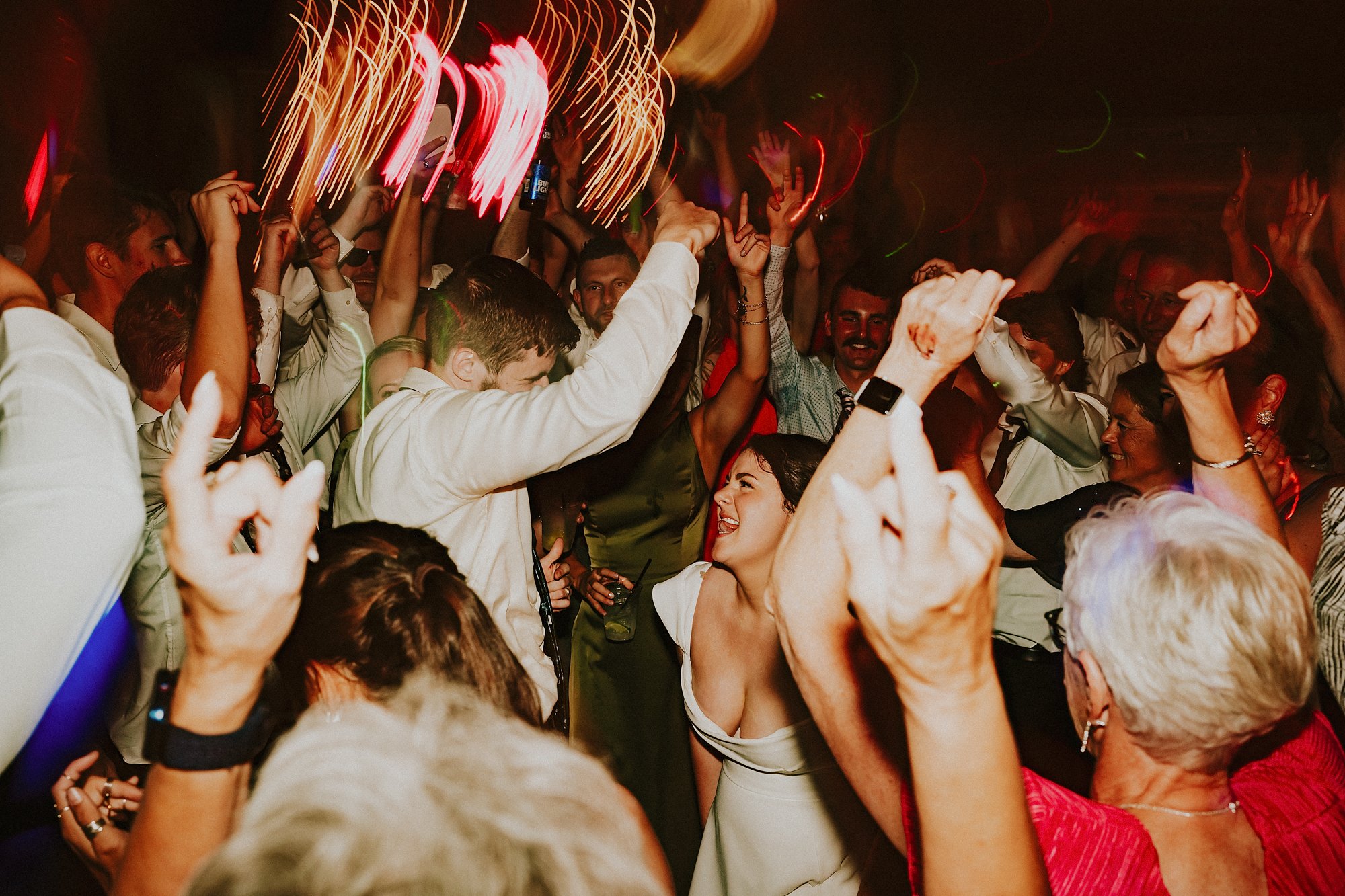 A Bride and Groom on the dance floor in Lake Bomoseen Lodge taproom. Surrounded by those they love most everyone dances in lively colourful lights.