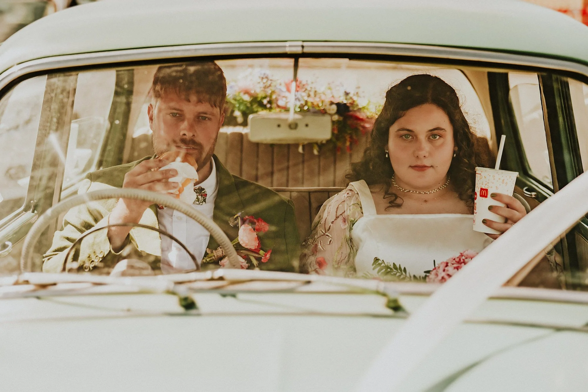 A moody wedding portrait of a Bride and Groom in a vintage car eating mcdonalds drive thru in this Lincolnshire wedding.