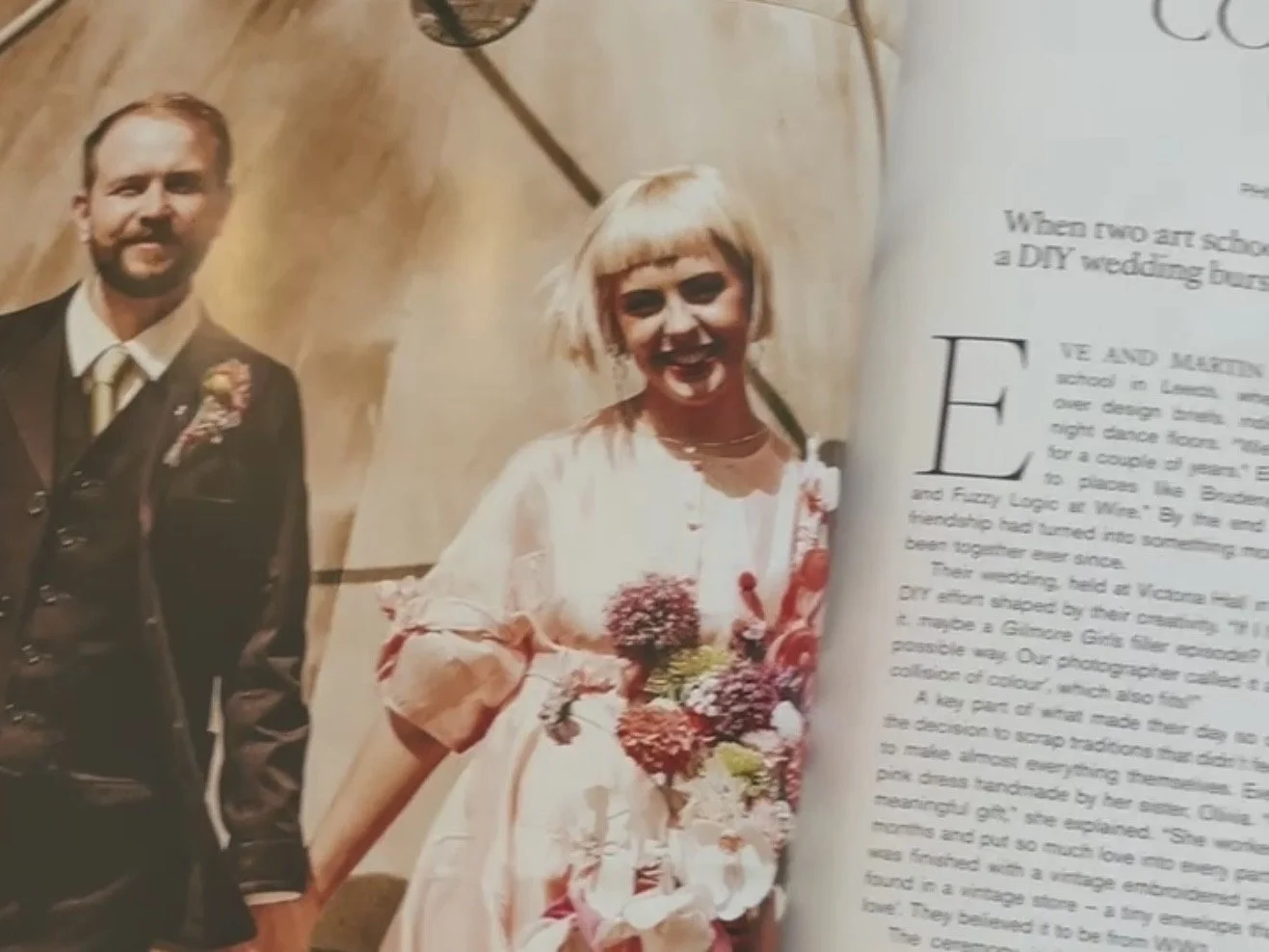 A wedding magazine page featuring a man in a suit and a woman in a white dress holding a bouquet of flowers, smiling in front of a wooden background.