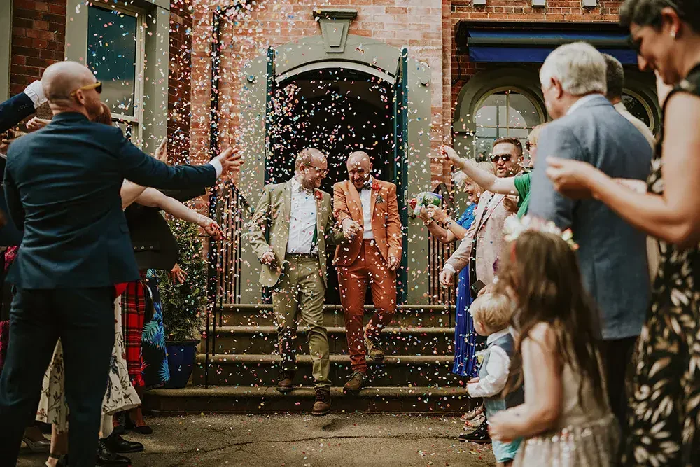 People celebrating outside a building with confetti falling.