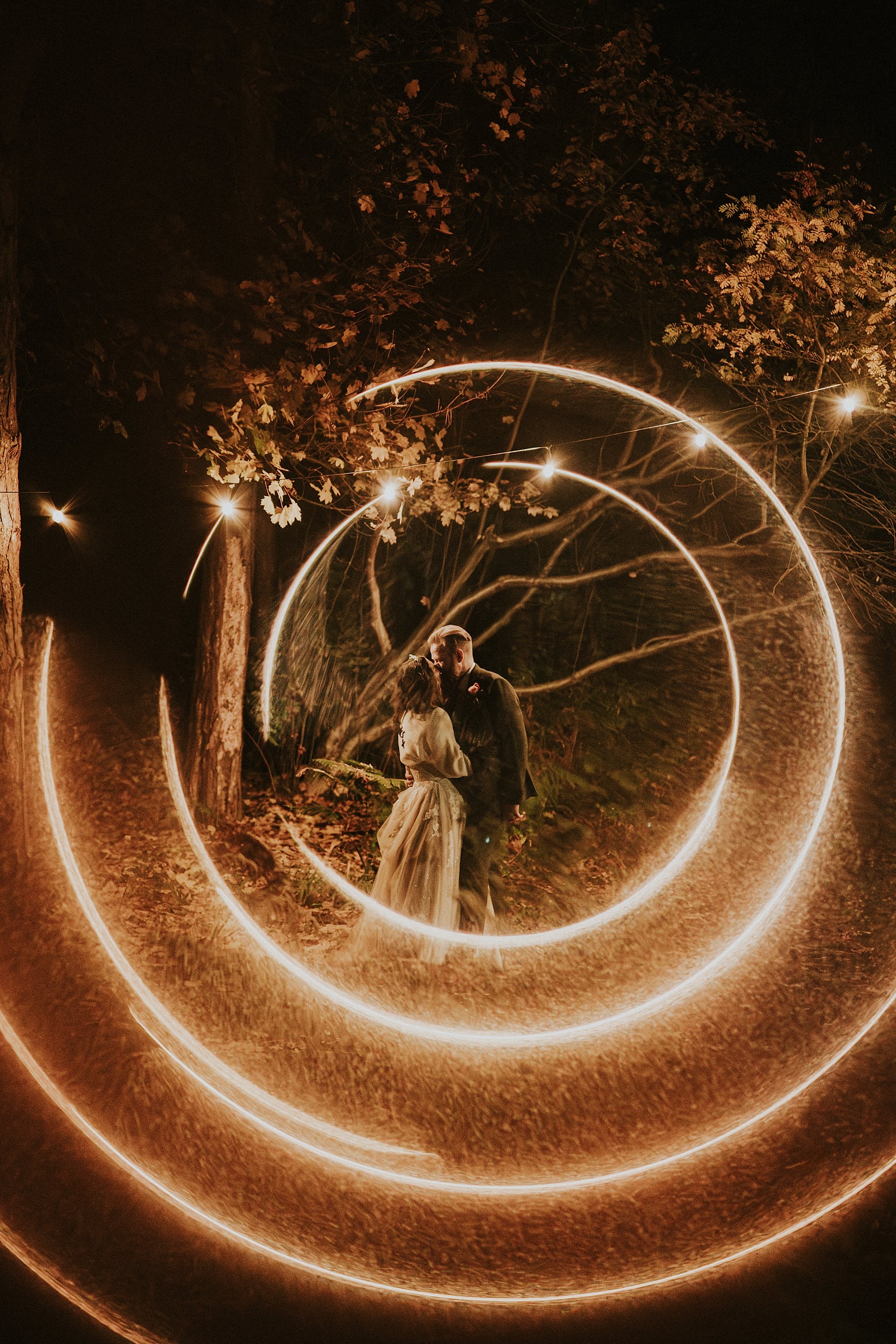 A night time portrait in the woods surrounding the Pumping house Ollerton. Rings of fire from festoon lighting frame a romantic ethereal kiss.