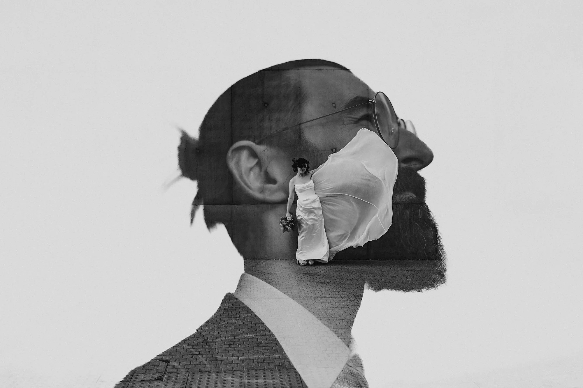 A double exposure of a wind blown wedding dress inside a Grooms head in black and white outside the Hepworth gallery in Wakefield.