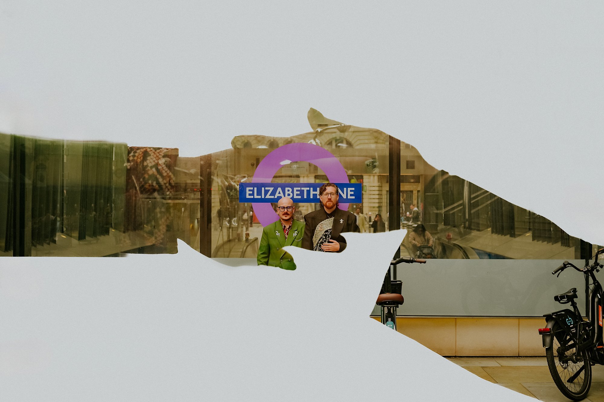 A double exposure of two grooms outside the Elizabeth line sign on the London underground. Funky wedding photography in London.