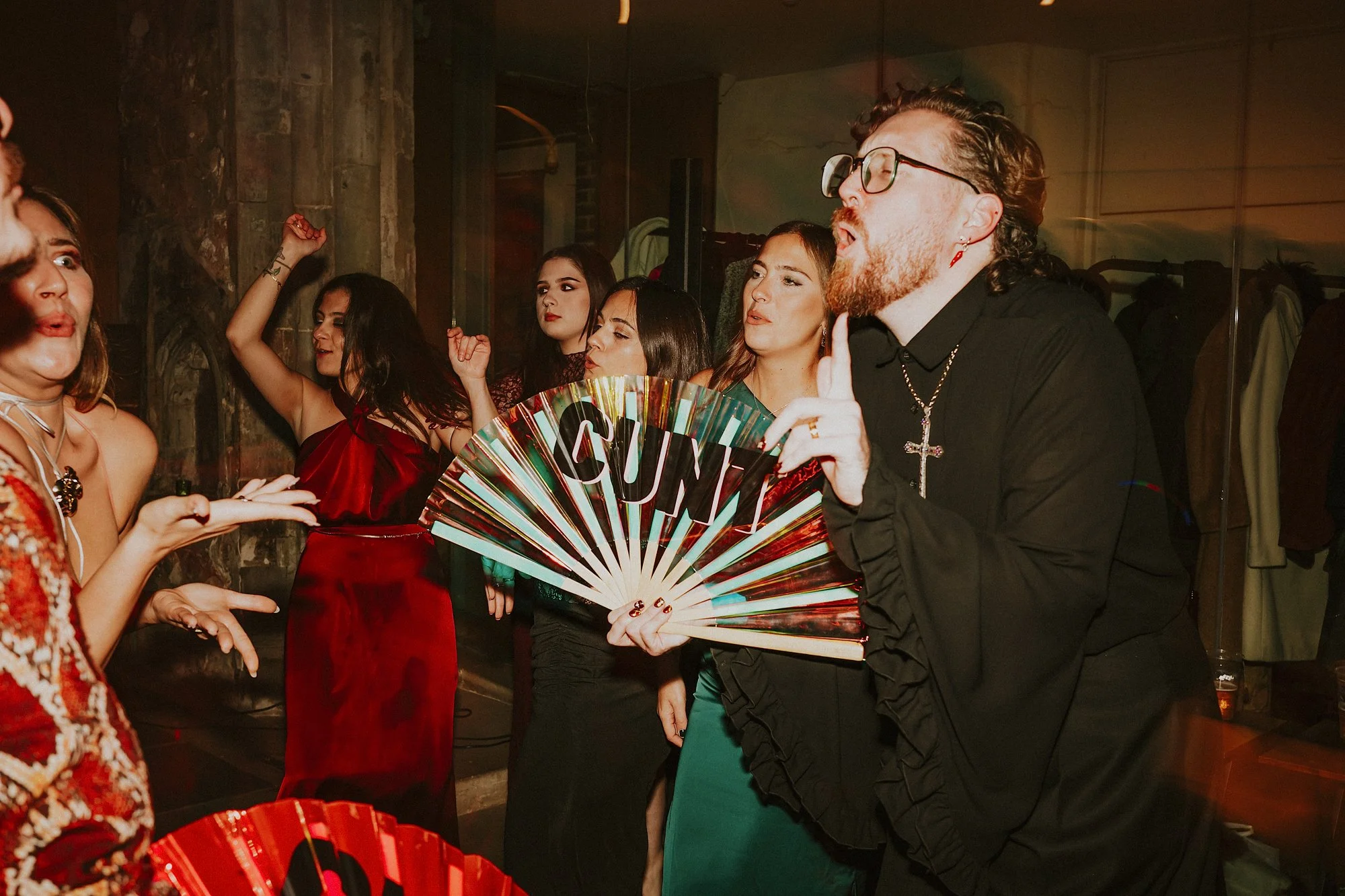 A funny dancing image of a Groom just married at St Ethelburga's Centre for Reconciliation and Peace. He points his finger while holding a fan.