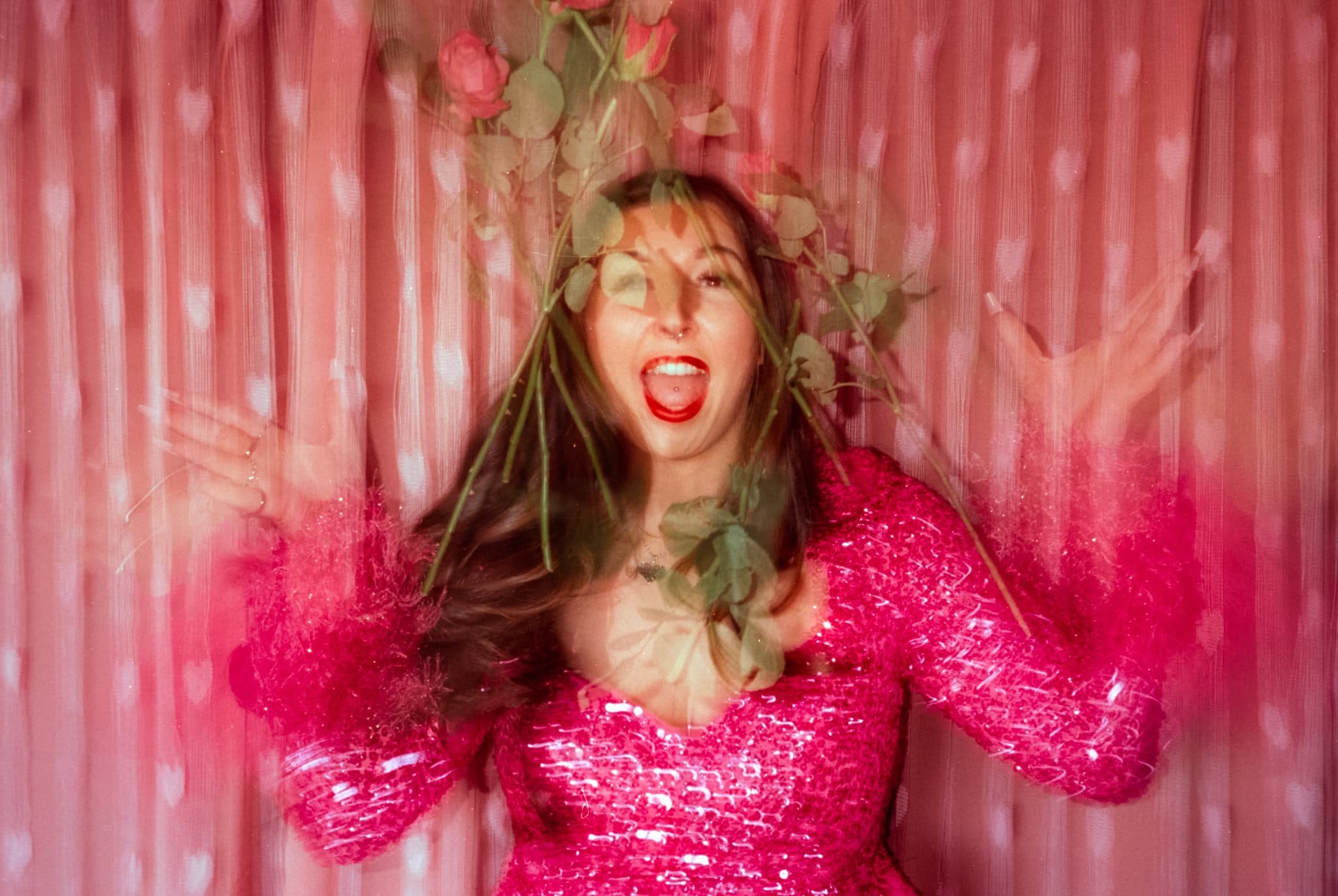 A portrait of a model in pink throwing roses and screaming