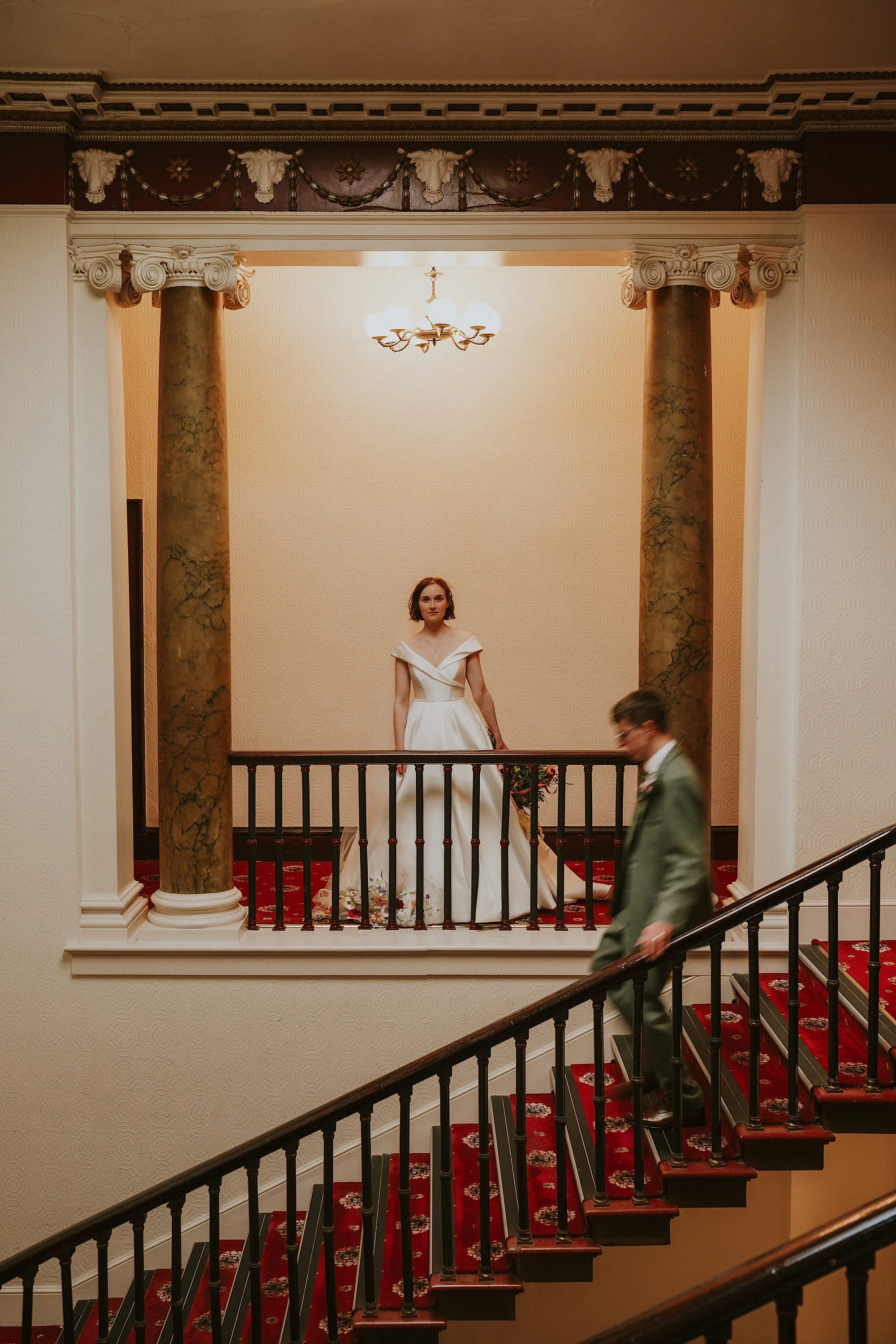 Wortley Hall wedding photography of a Bride & Groom on the grand staircase. The Bride poses while the Groom walks down the stairs.