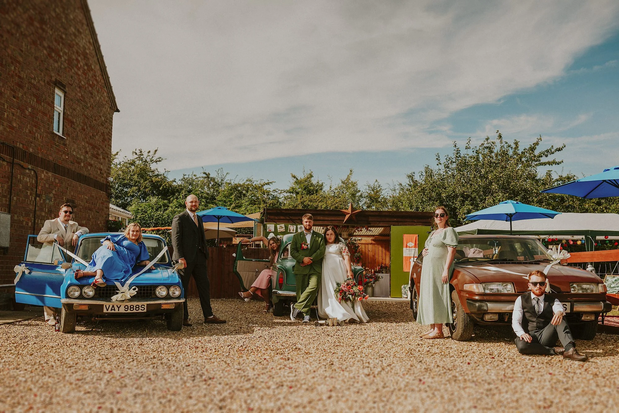 Cool Lincolnshire wedding photography. The wedding party pose around vintage cars.