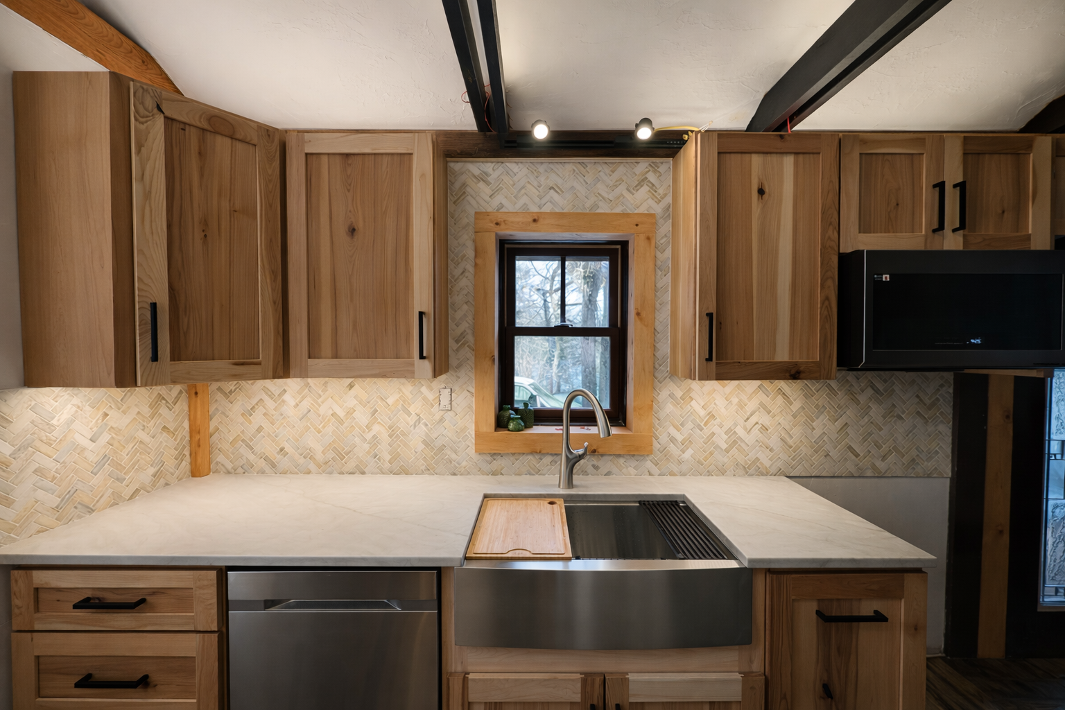 Kitchen with wooden cabinets, a window, a marble countertop, a stainless steel sink with a wooden cover, and a small microwave in a modern design.