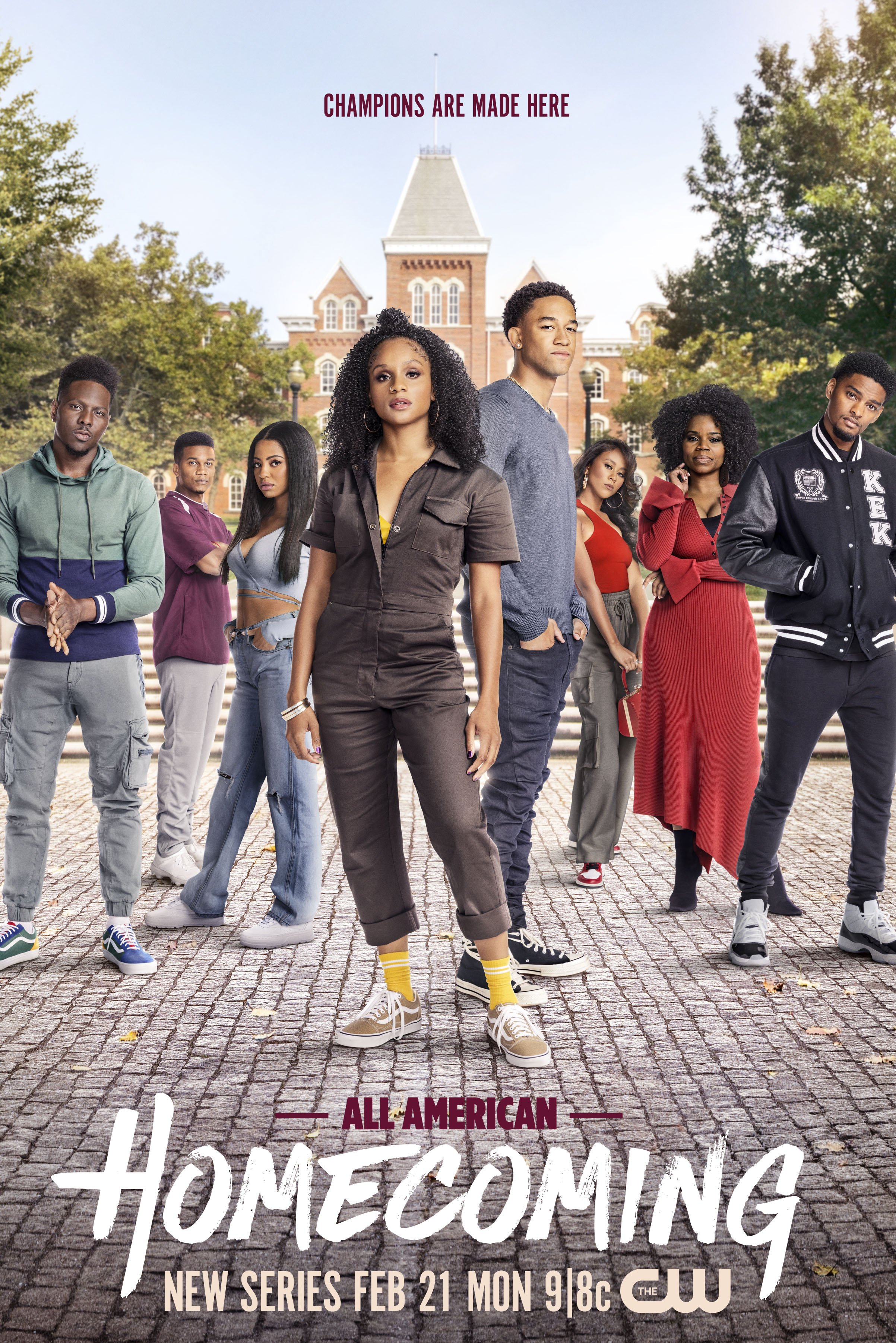 A group of diverse young adults standing on a cobblestone street in front of a large historic building with a tower and trees around. The image promotes a TV series titled 'Homecoming' airing on The CW, starting February 21st.