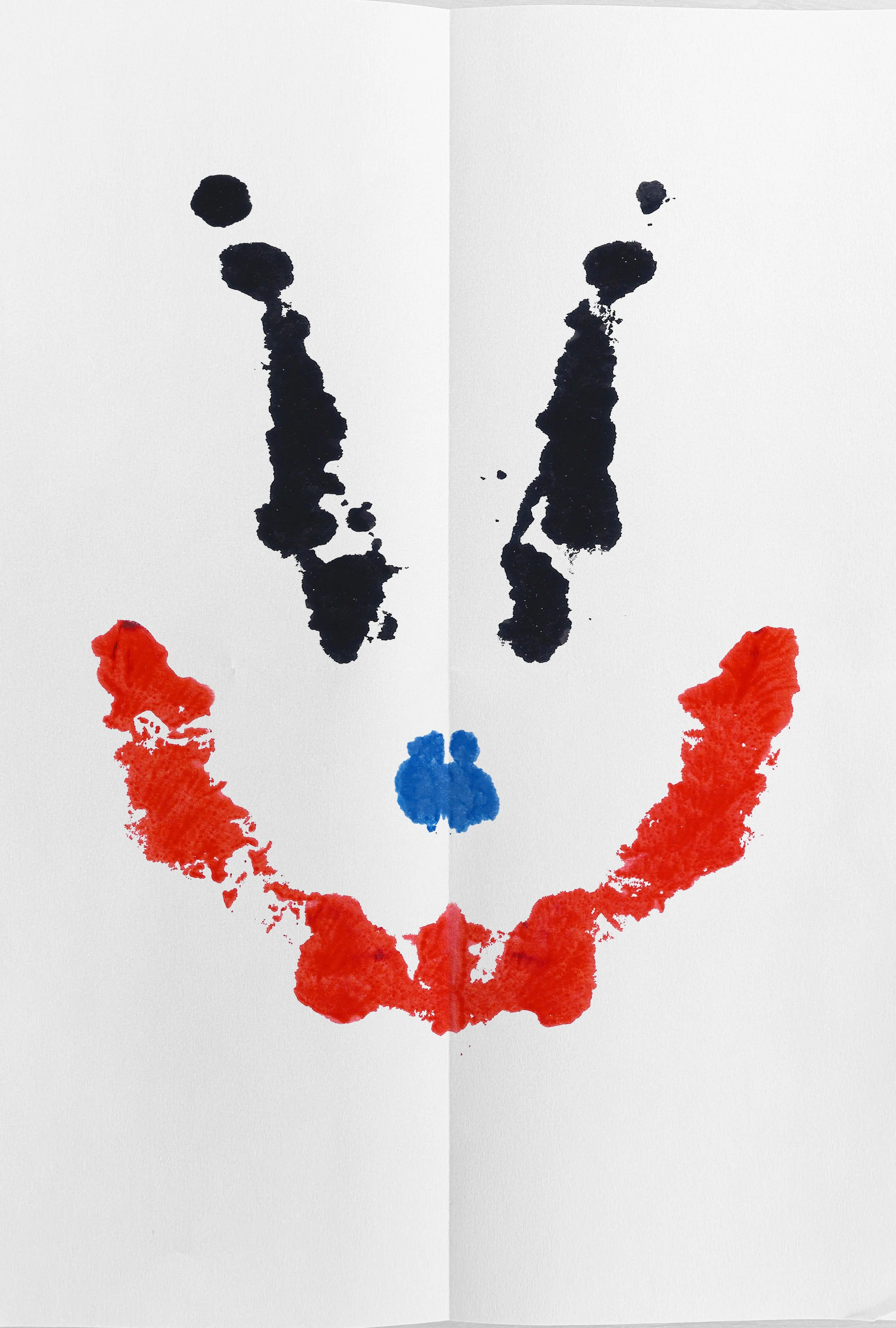 Abstract inkblot pattern resembling a symmetrical butterfly or face, with red and blue accents on white paper.