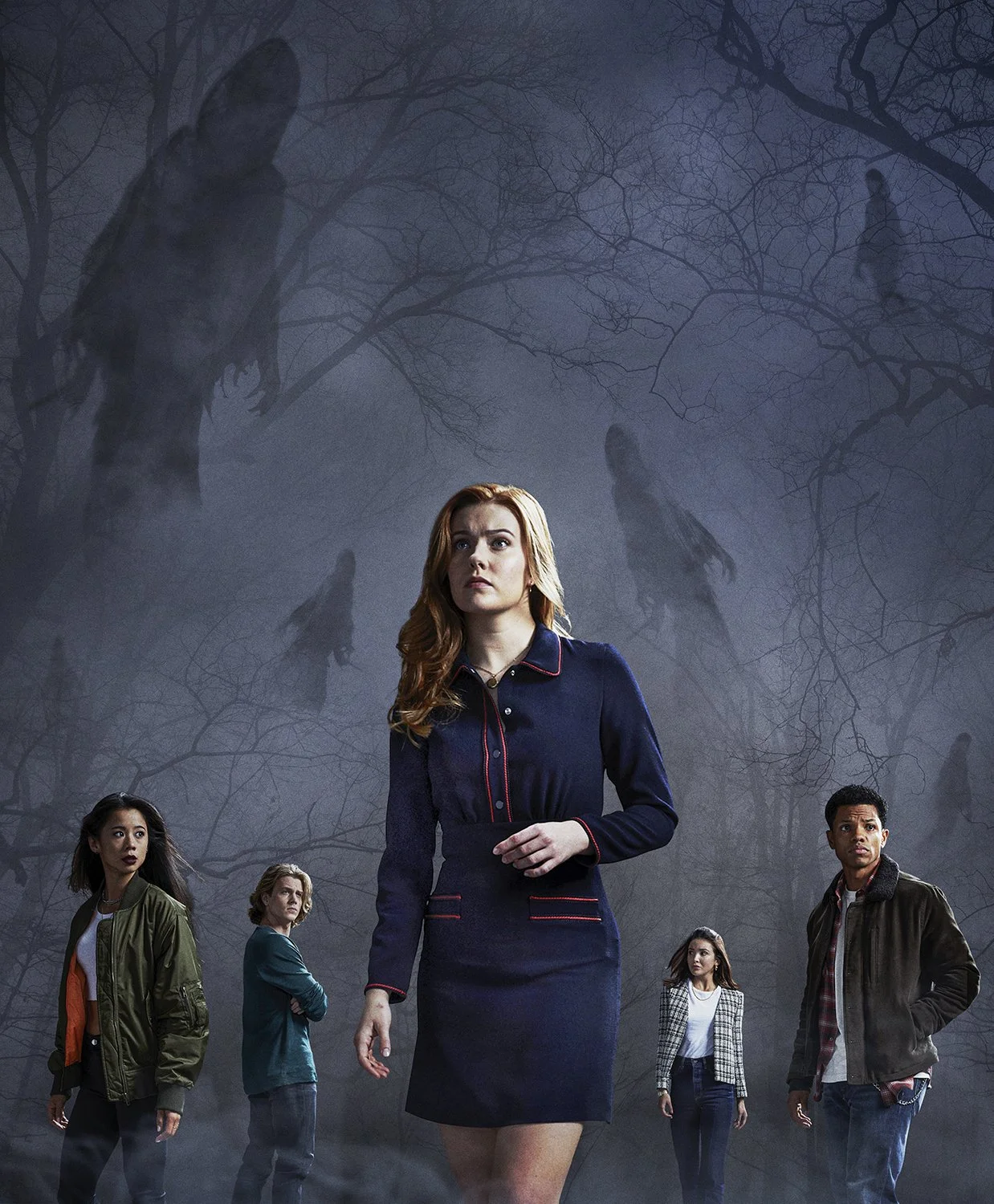 A woman with red hair and a navy blue dress stands in the foreground, surrounded by four other young adults with serious expressions. In the background, shadowy ghostly figures and faces are visible among dark, leafless trees in a foggy, eerie settin