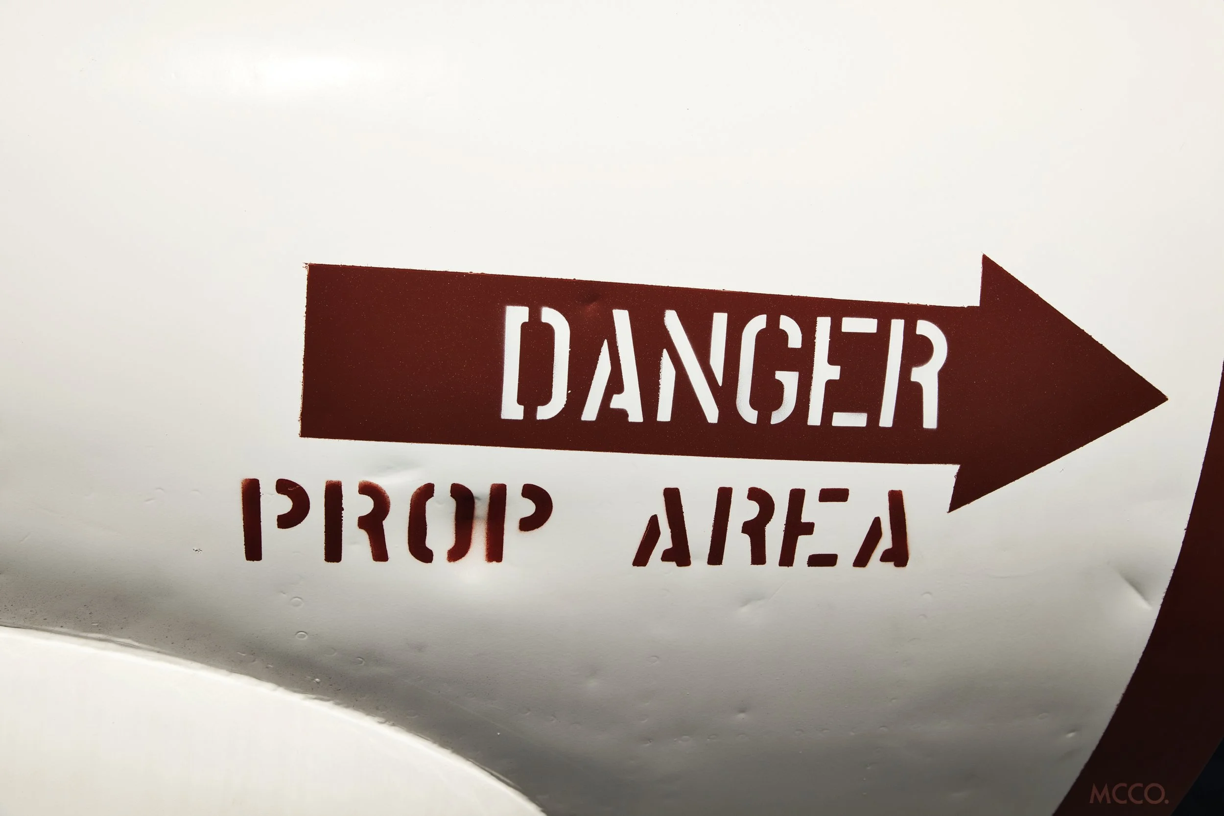 Red arrow-shaped sign with the word 'DANGER' in white capital letters pointing to the right, partially visible, on a white background.