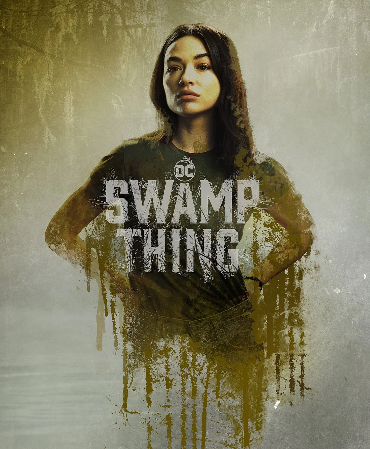 Poster of a woman with dark hair, wearing a black t-shirt that says "SWAMP THING" and has a small DC logo. The background appears to be a grungy, wooded area with a yellowish tint, and there are paint-like splashes and drips over the image, giving it