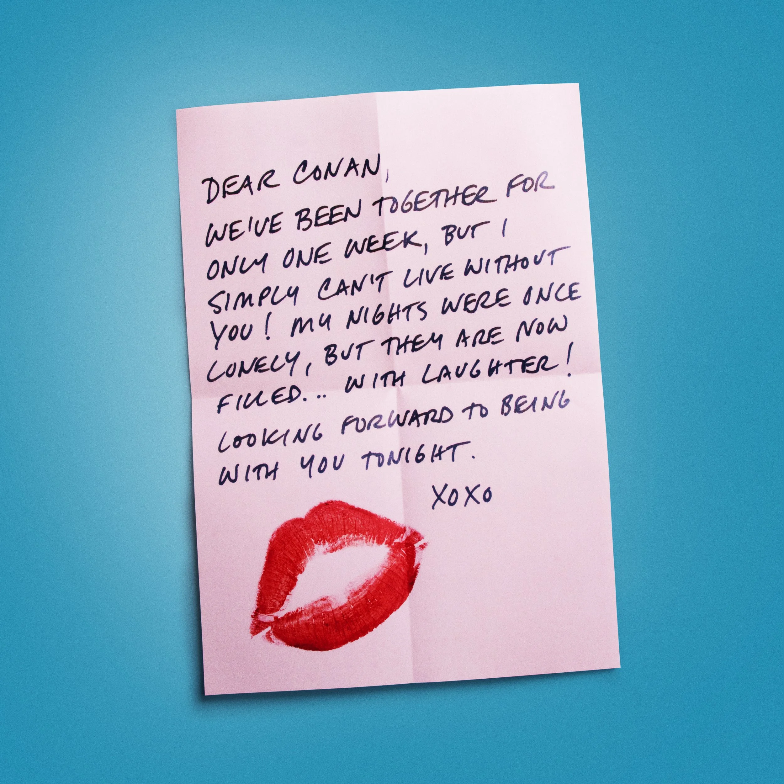 A pink sticky note with handwritten text and a red lipstick kiss mark on a blue background.