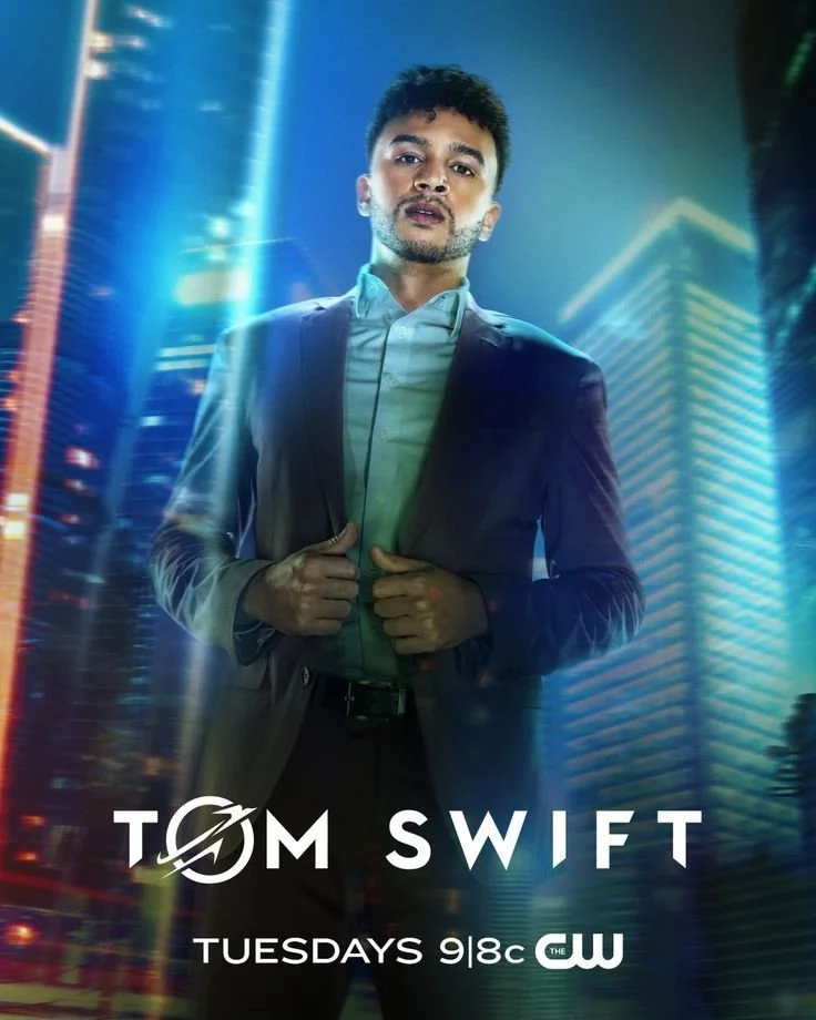 Promotional poster for the TV show 'Tom Swift' featuring a man in a suit standing against a cityscape at night, with bright lights and tall buildings in the background.