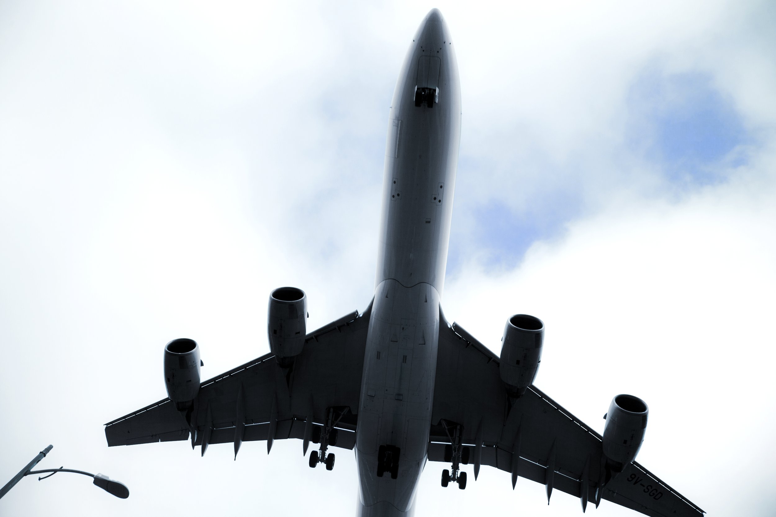 A large commercial airplane flying overhead in the sky, viewed from below.