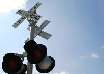 A railroad crossing signal with red lights and crossbucks indicating a railroad crossing.