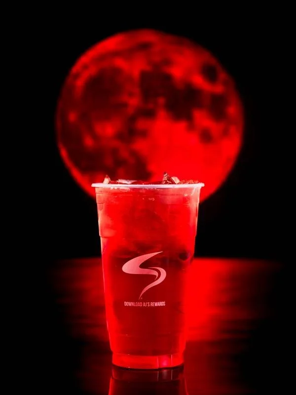 Iced red drink in plastic cup with logo, red moon background.