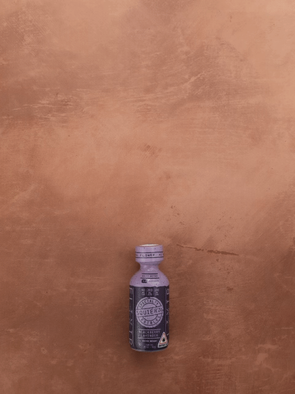 Small purple bottle labeled "Squeeze D Rip N Sip" on a brown textured surface.