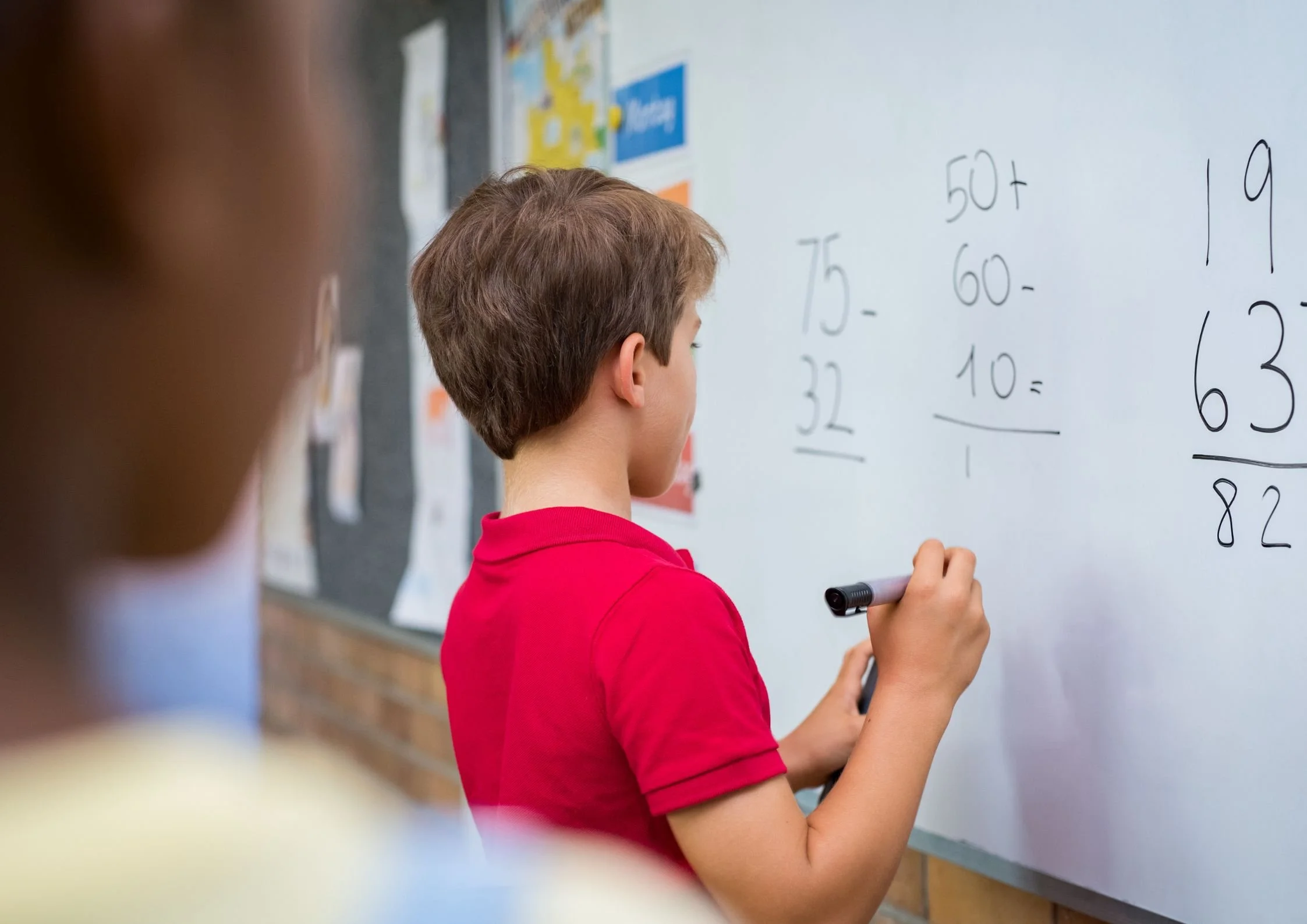 A U2 Tuition student practicing maths equations on a whiteboard