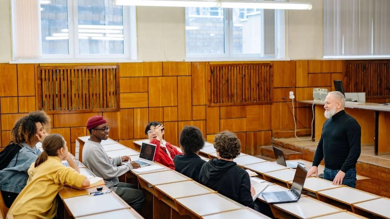 Law students discussing ideas with a university lecturer while preparing to study Law at a UK university