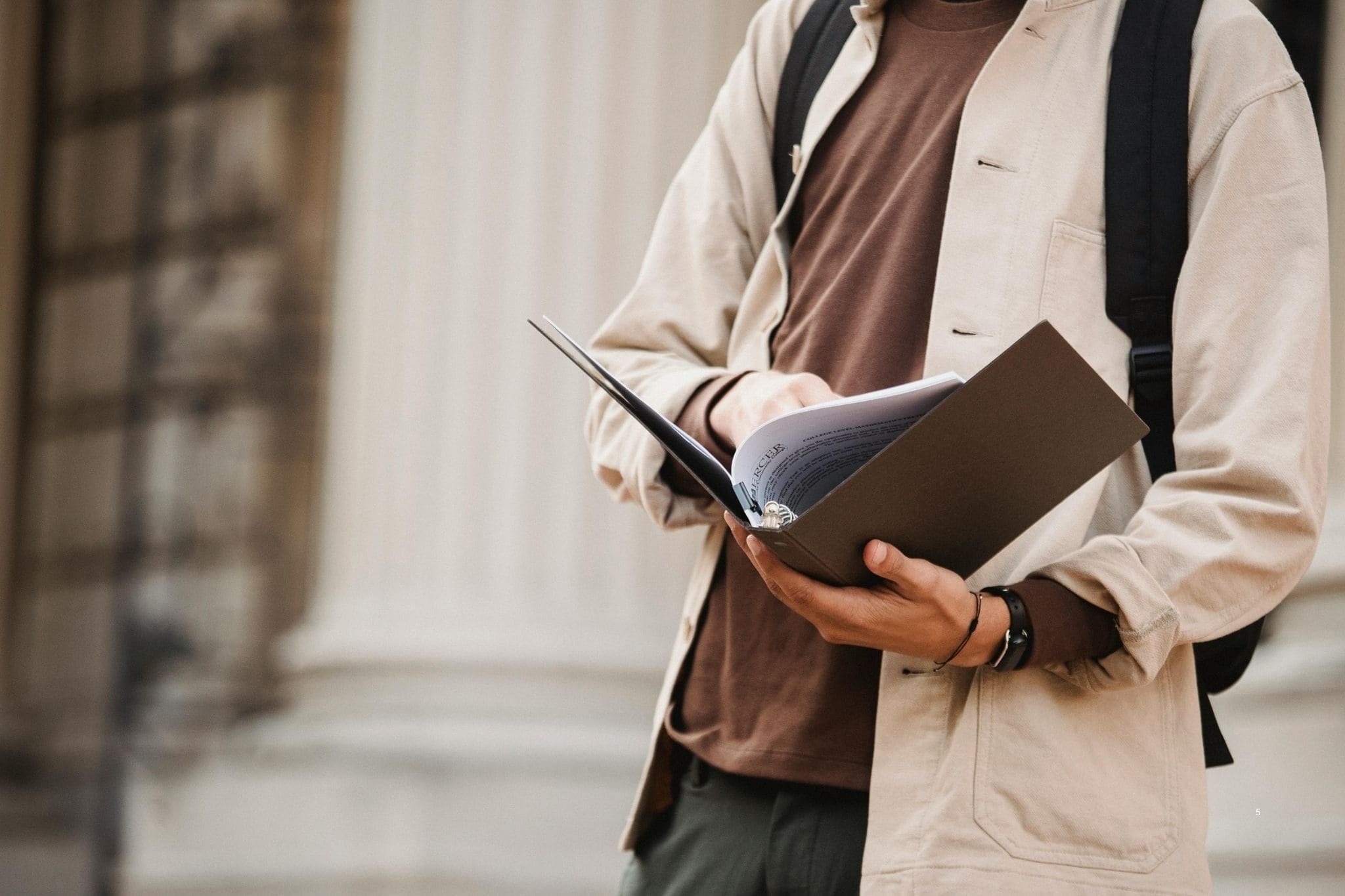 Student exploring Durham University, holding course materials and a notebook