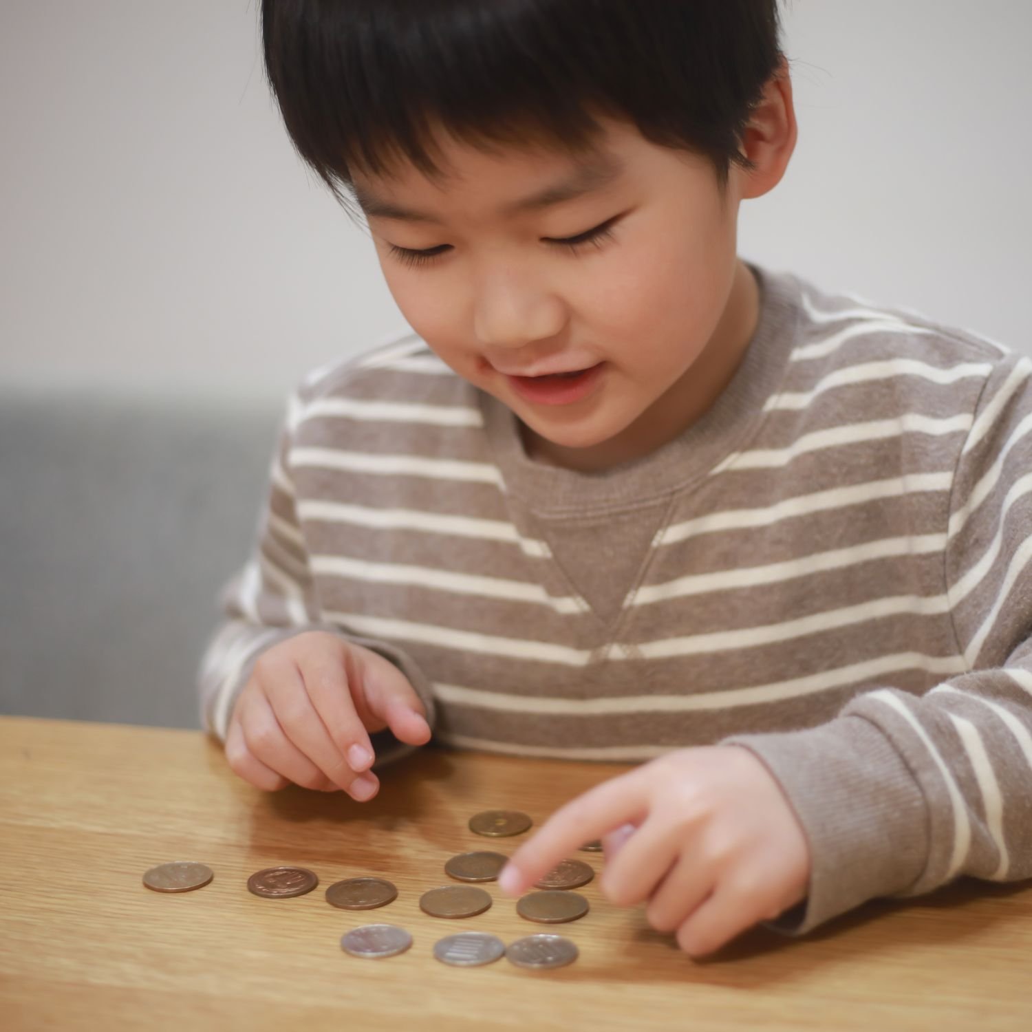 A U2 Tuition 11+ student sits counting coins whilst practicing maths skills.