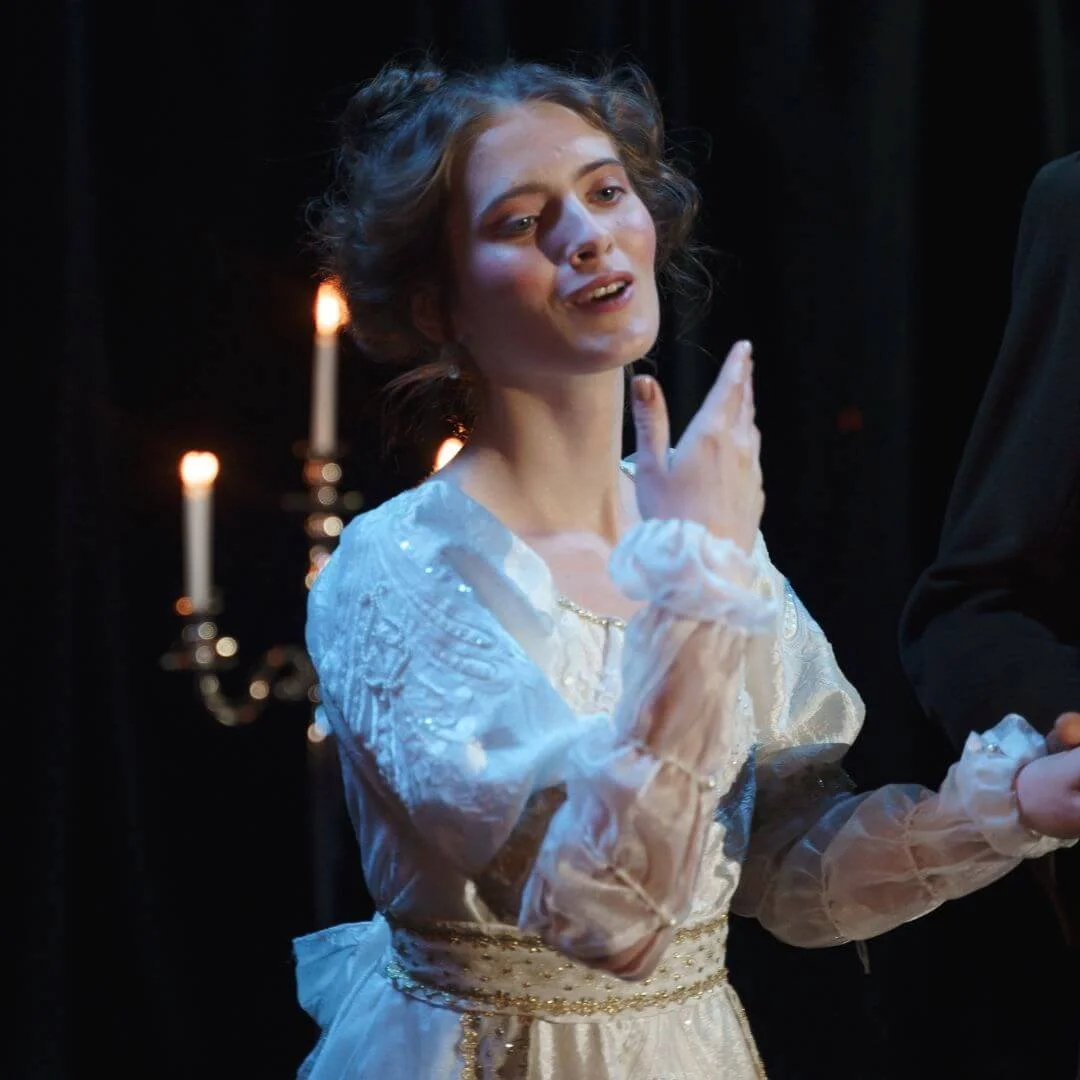 Young female actress in period dress performing a dramatic monologue during a U2 Tuition LAMDA acting exam preparation session.