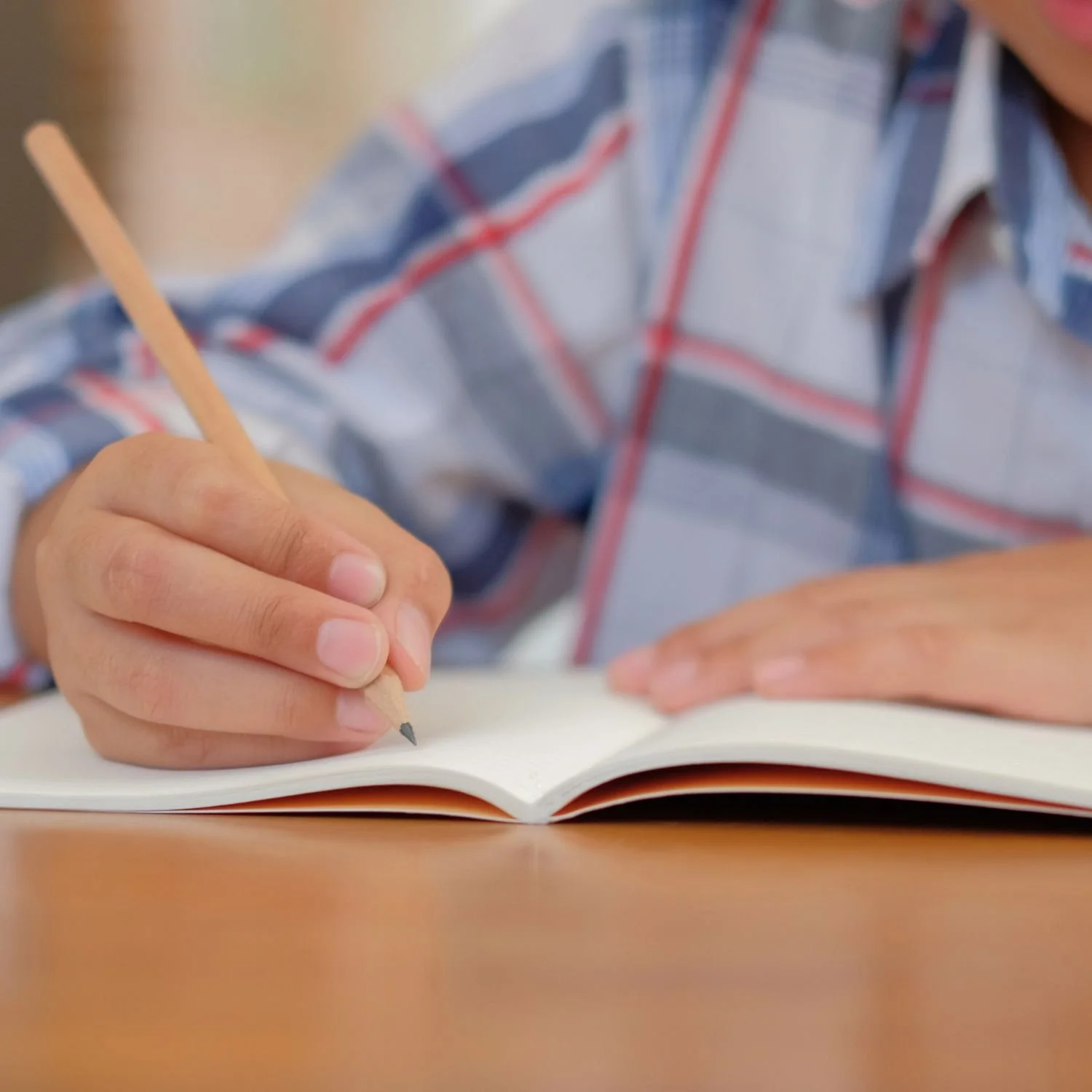 A U2 Tuition student writing a story in their workbook.