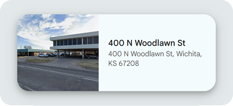 A commercial building with a parking lot and some cars parked in front, under a partly cloudy sky.