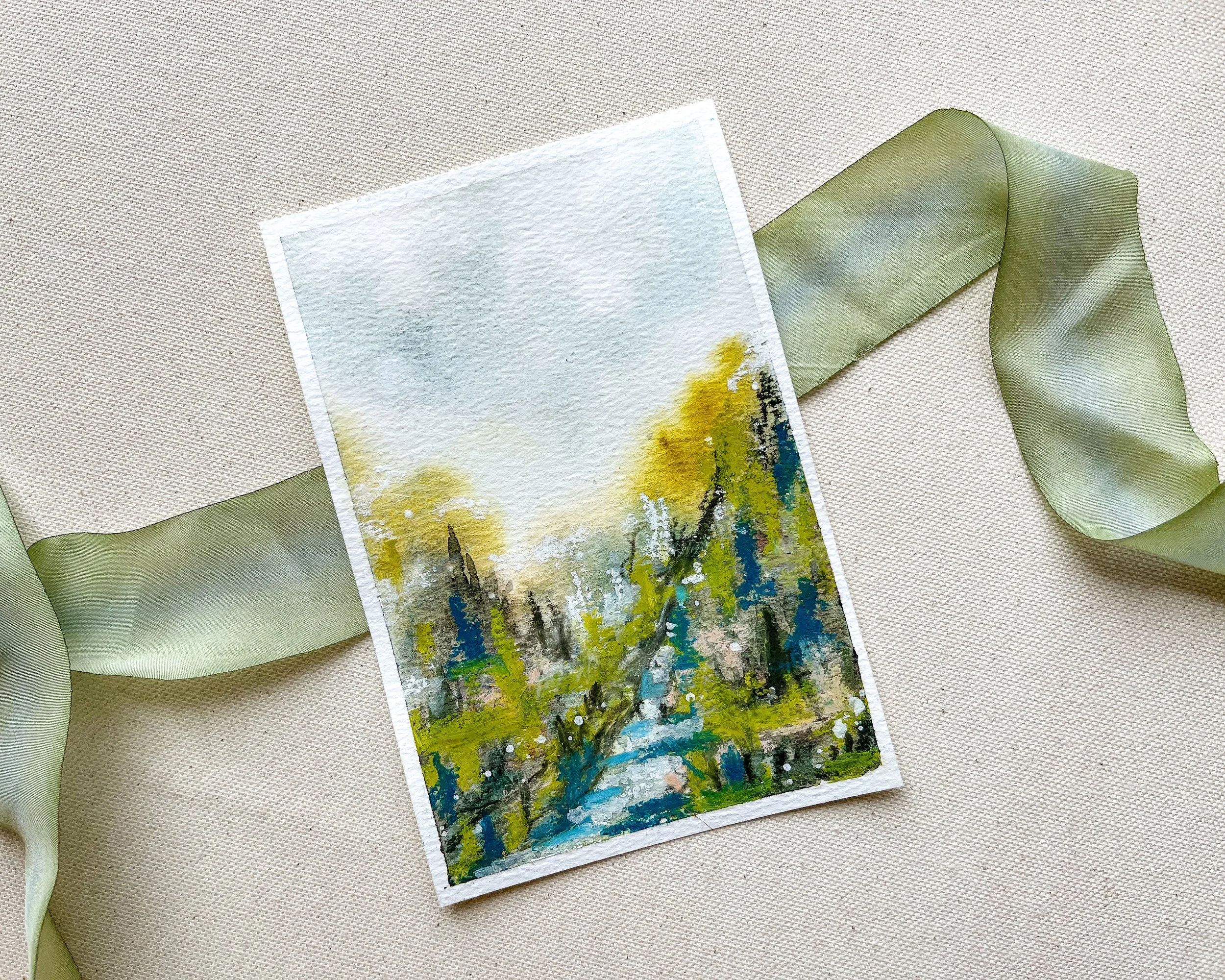 Mixed media landscape in watercolor and pastels on canvas background with green silk ribbon