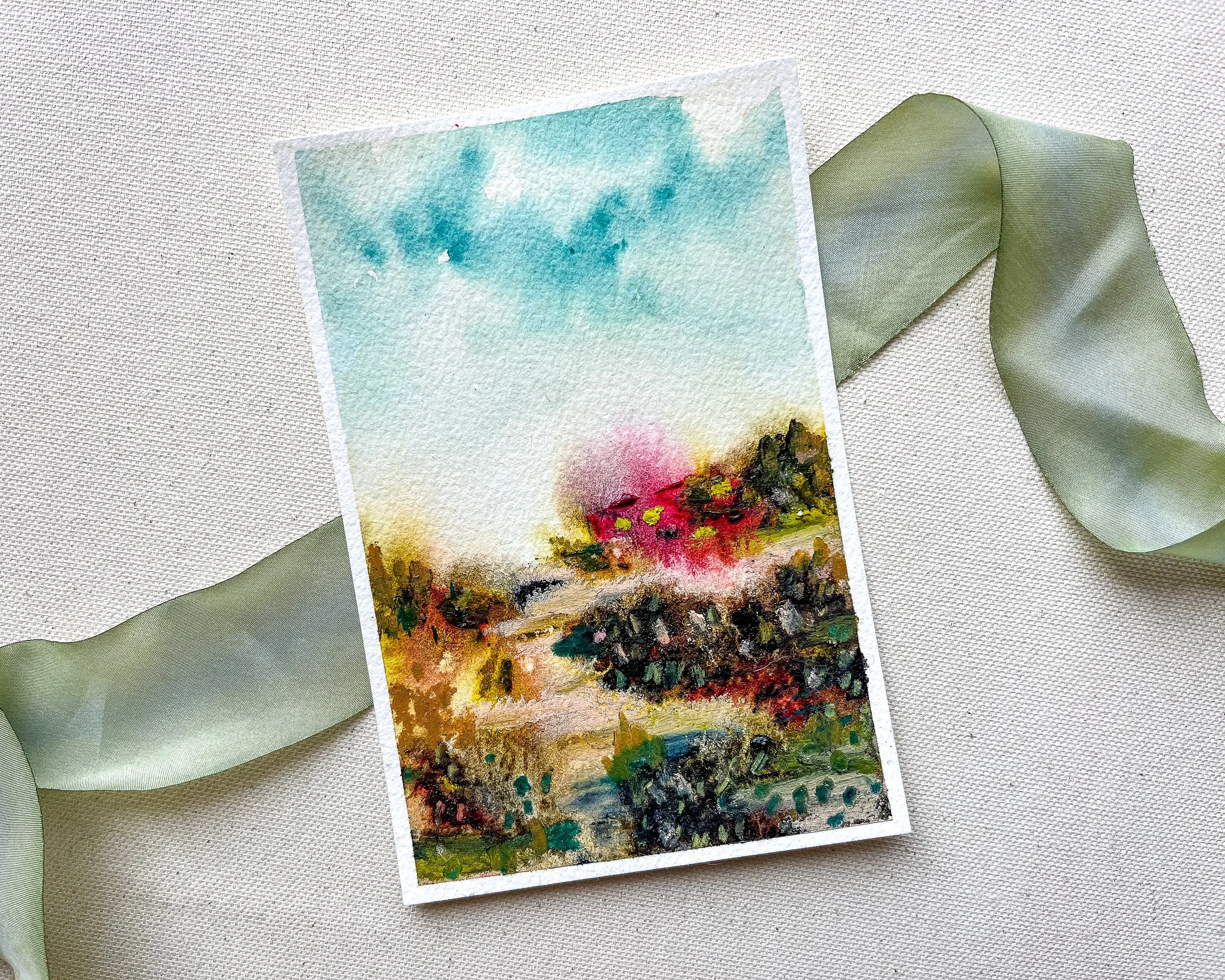 Mixed media landscape abstract painting on canvas background atop a green silk ribbon