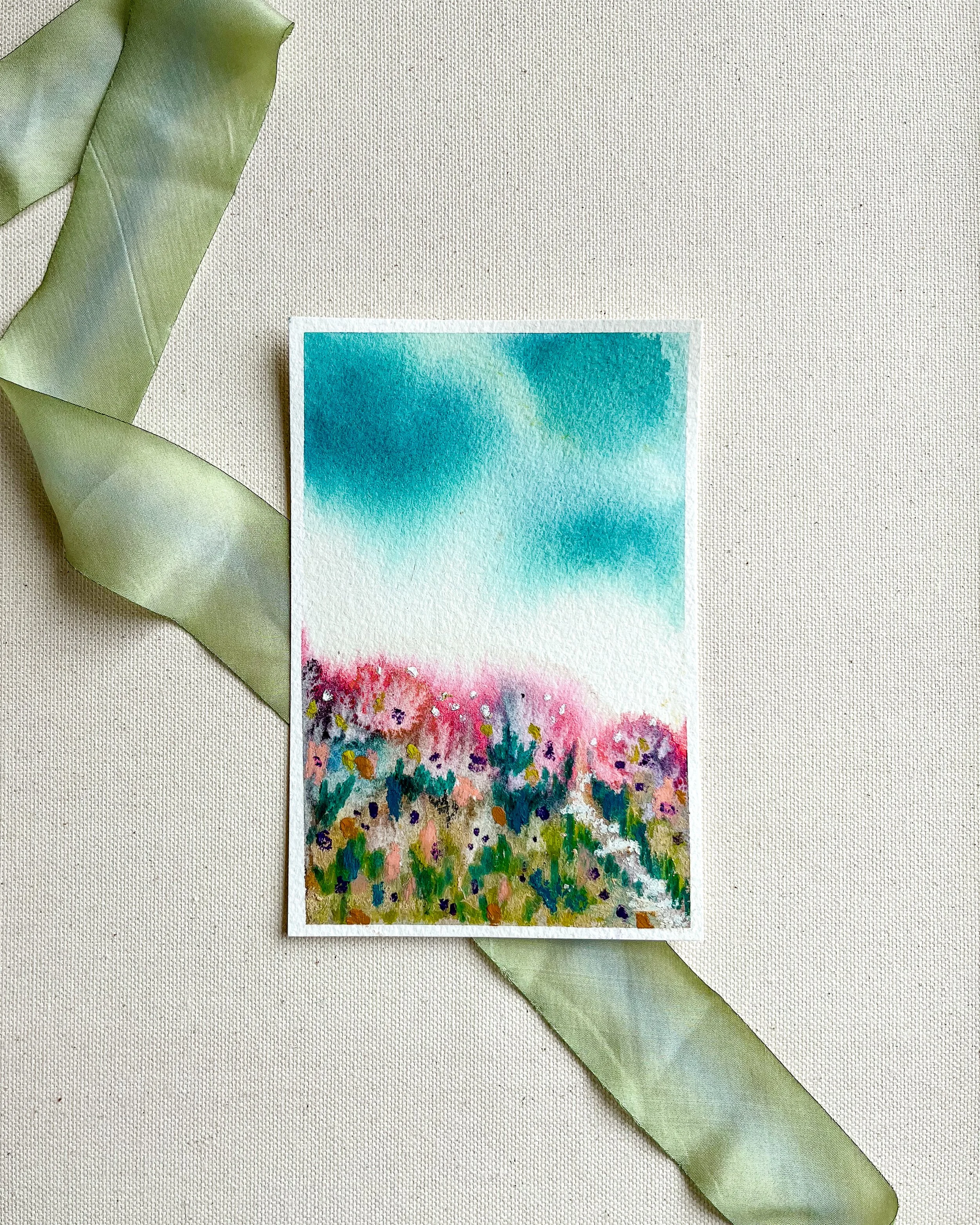 Full view of 4" x 6" mixed media abstract floral landscape painting atop a canvas background and green silk ribbon